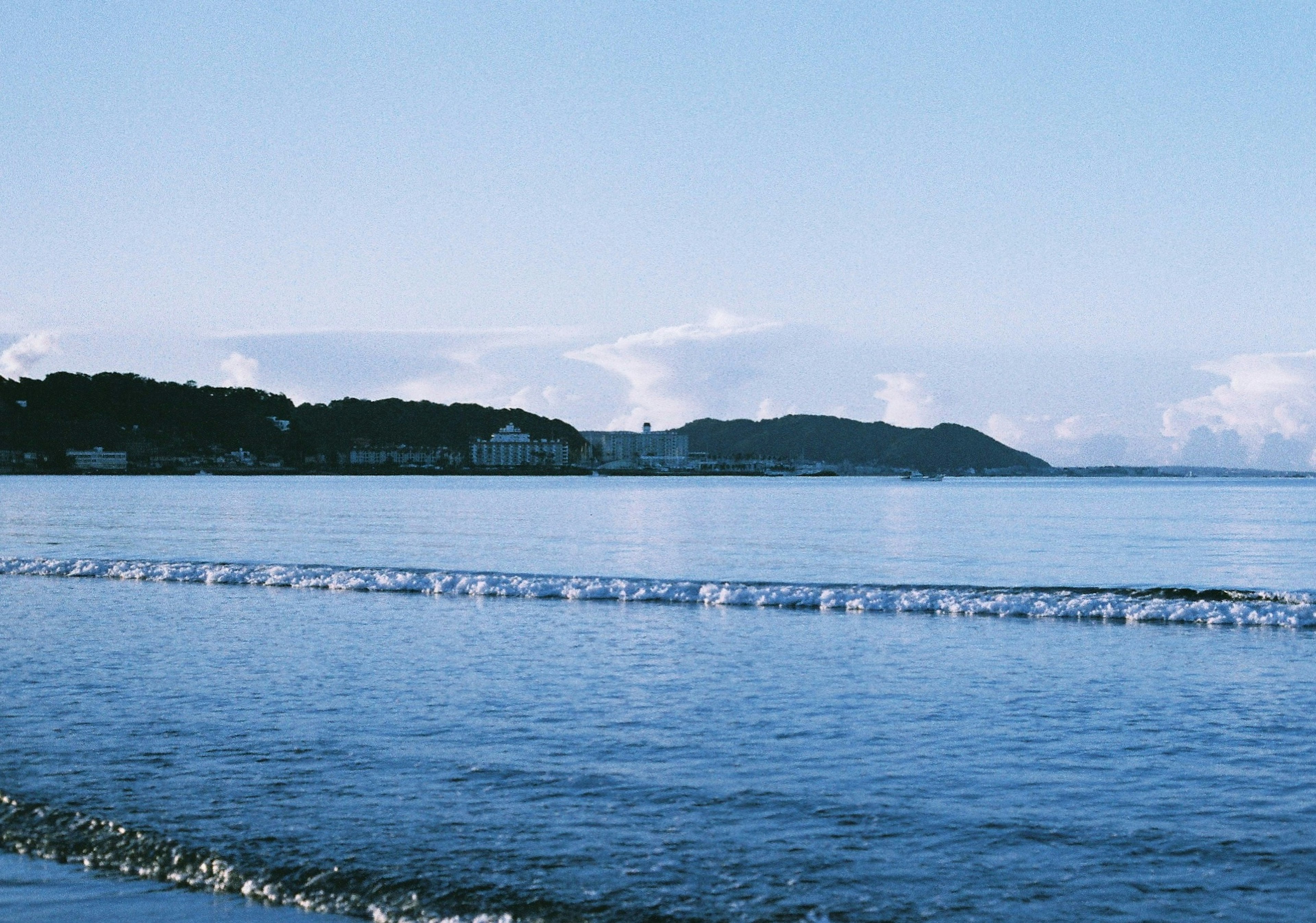 穏やかな海と青い空の風景 海岸線と山々が見える