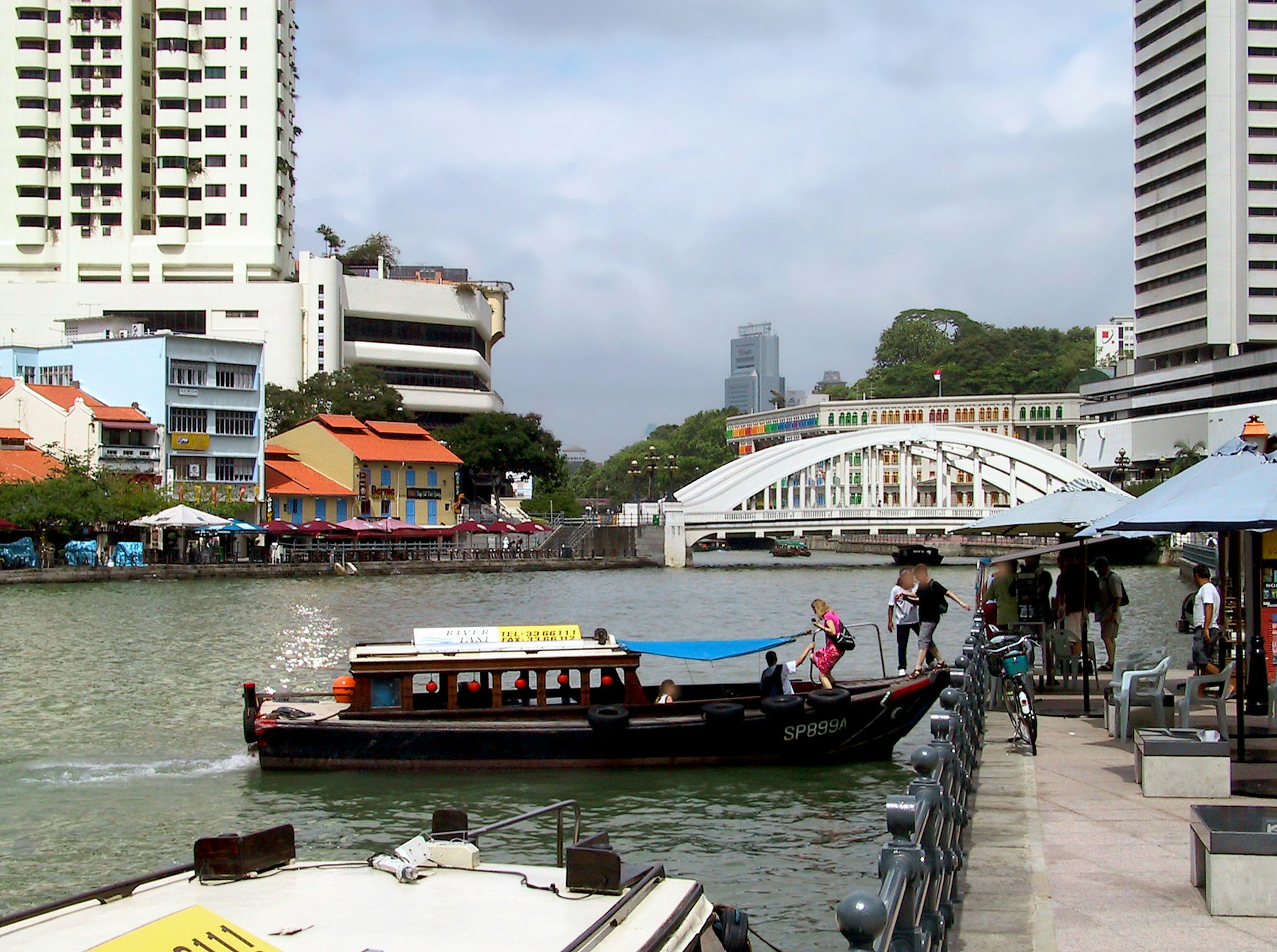 เรือในแม่น้ำที่คลาร์กคีย์ สิงคโปร์ พร้อมอาคารสีสันสดใสและสถาปัตยกรรมทันสมัย