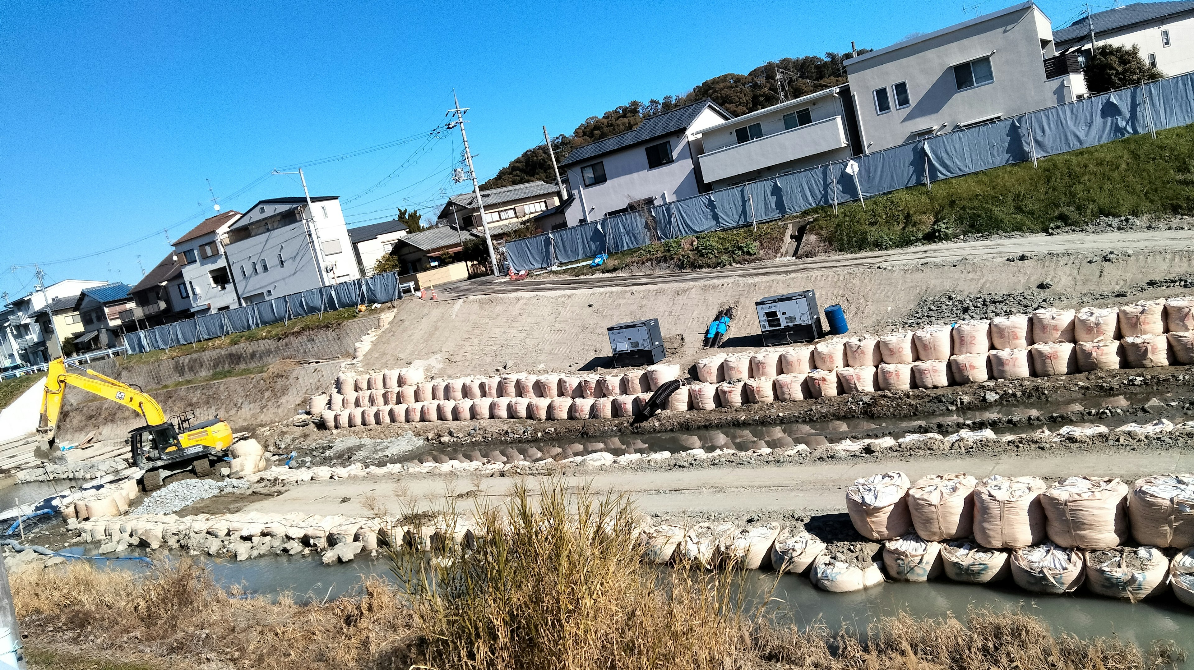 Construction site along a river with trucks and heavy machinery