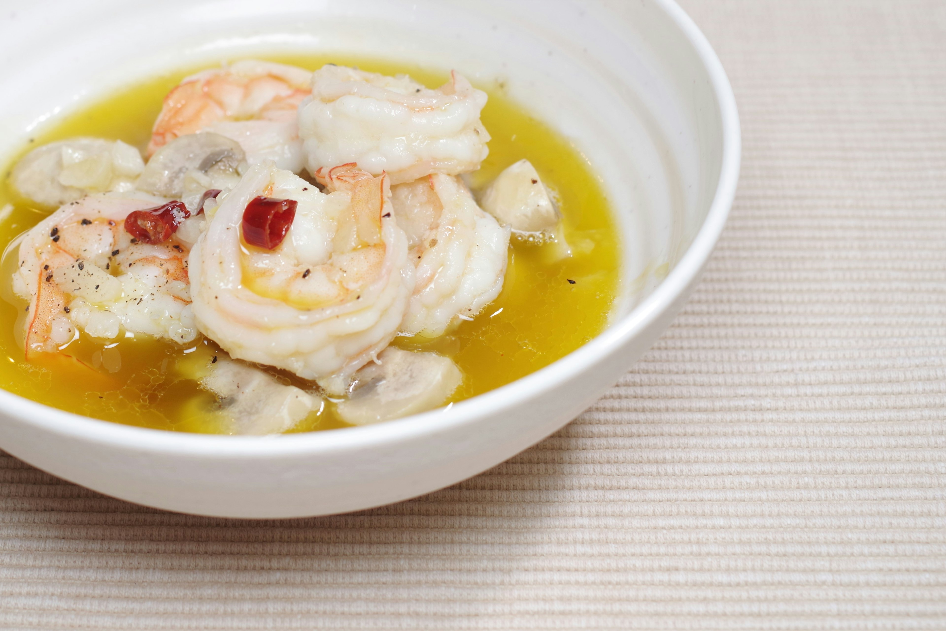 Plato de camarones servido en un tazón blanco con aceite de oliva