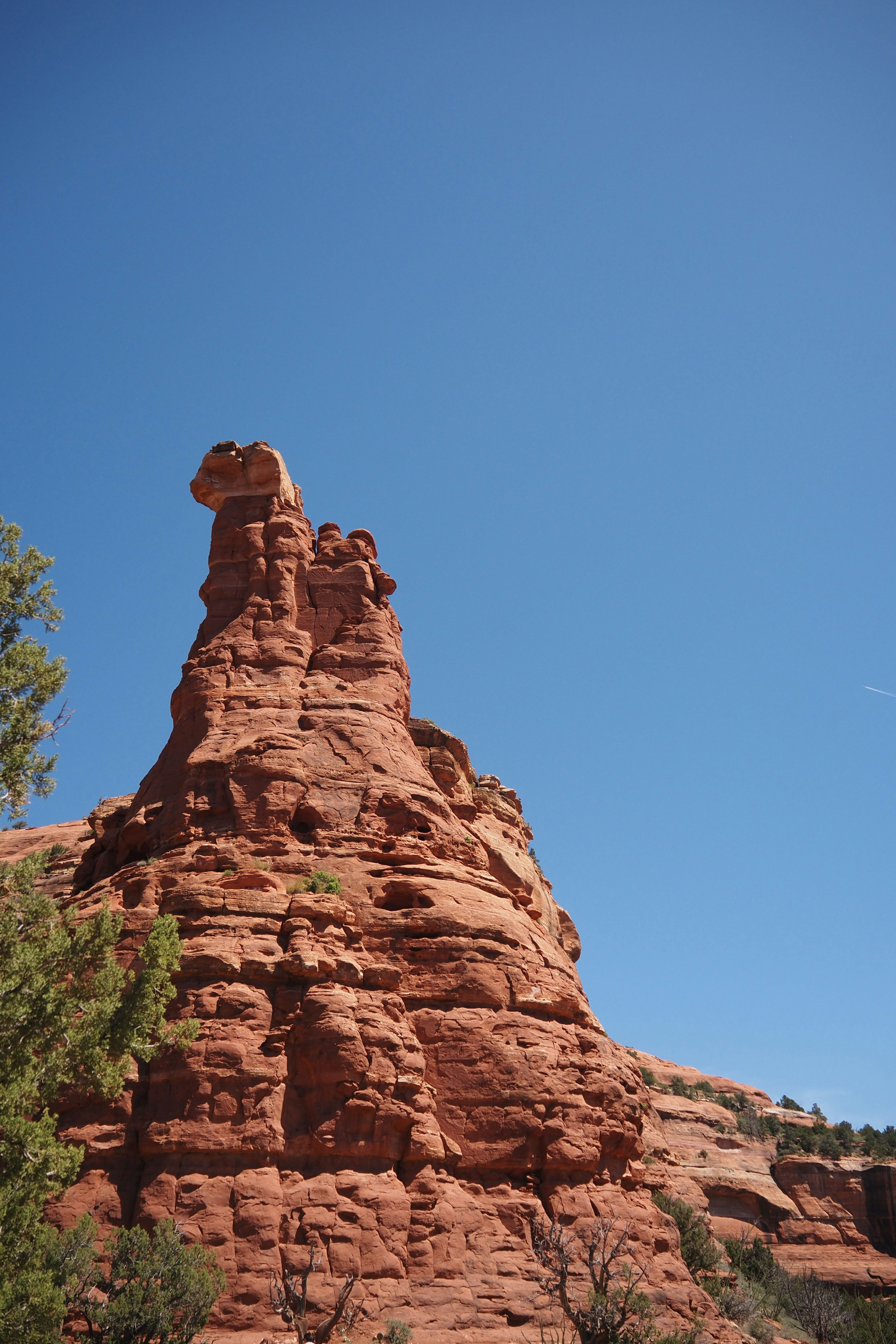 A towering red rock formation against a clear blue sky