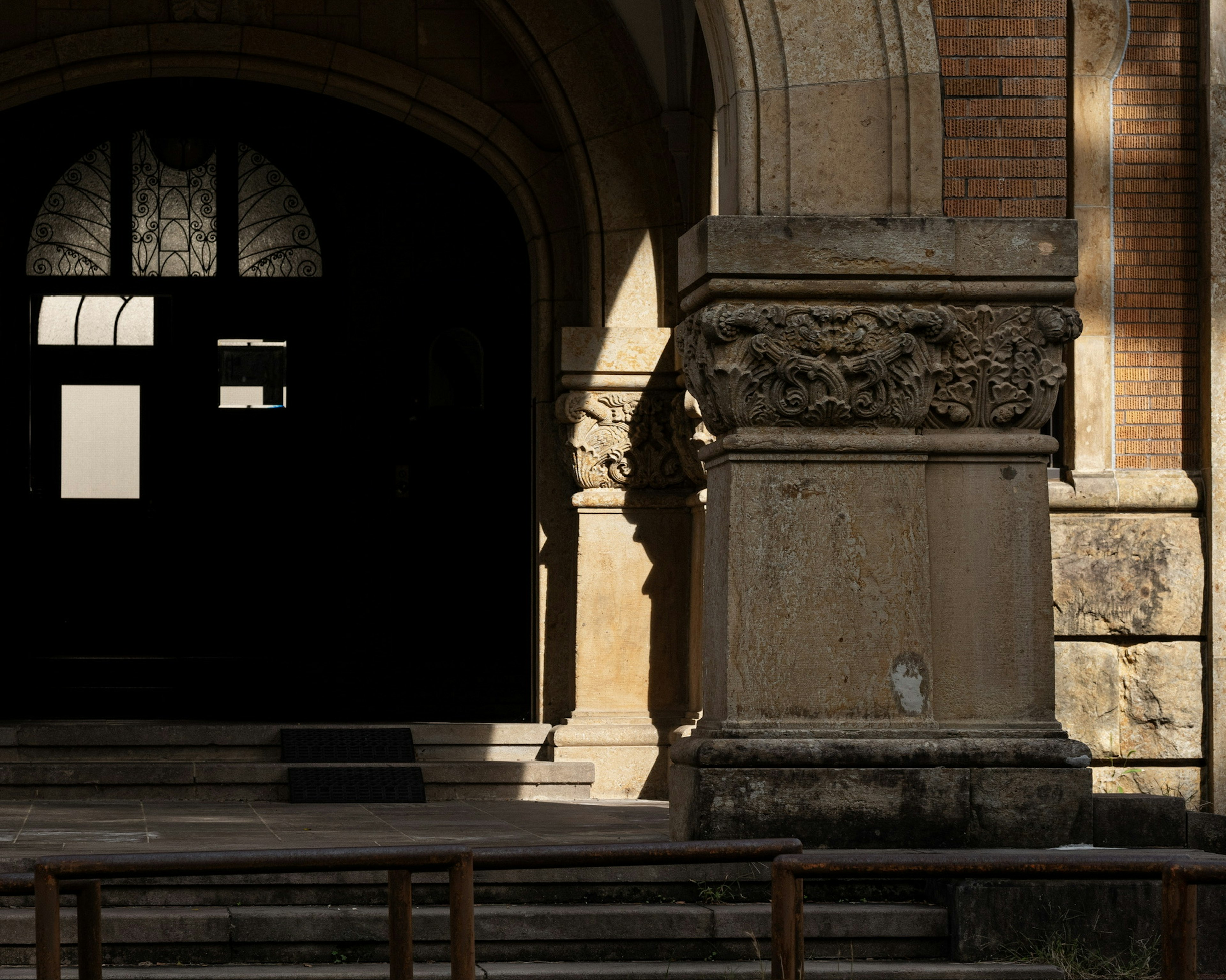 Entrance of a classical building featuring ornate columns and striking shadows