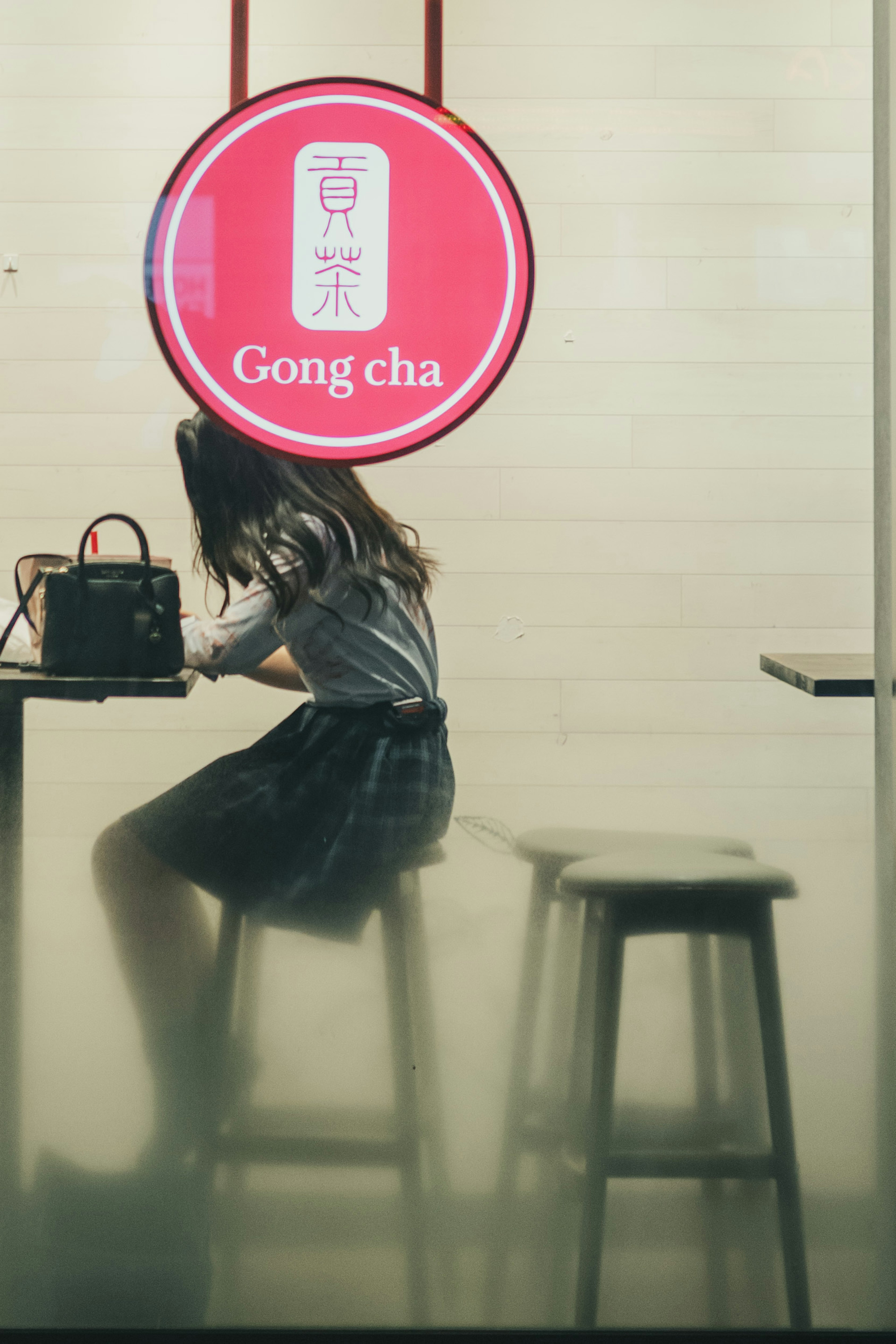 Silhouette de una mujer sentada bajo un letrero de Gong cha