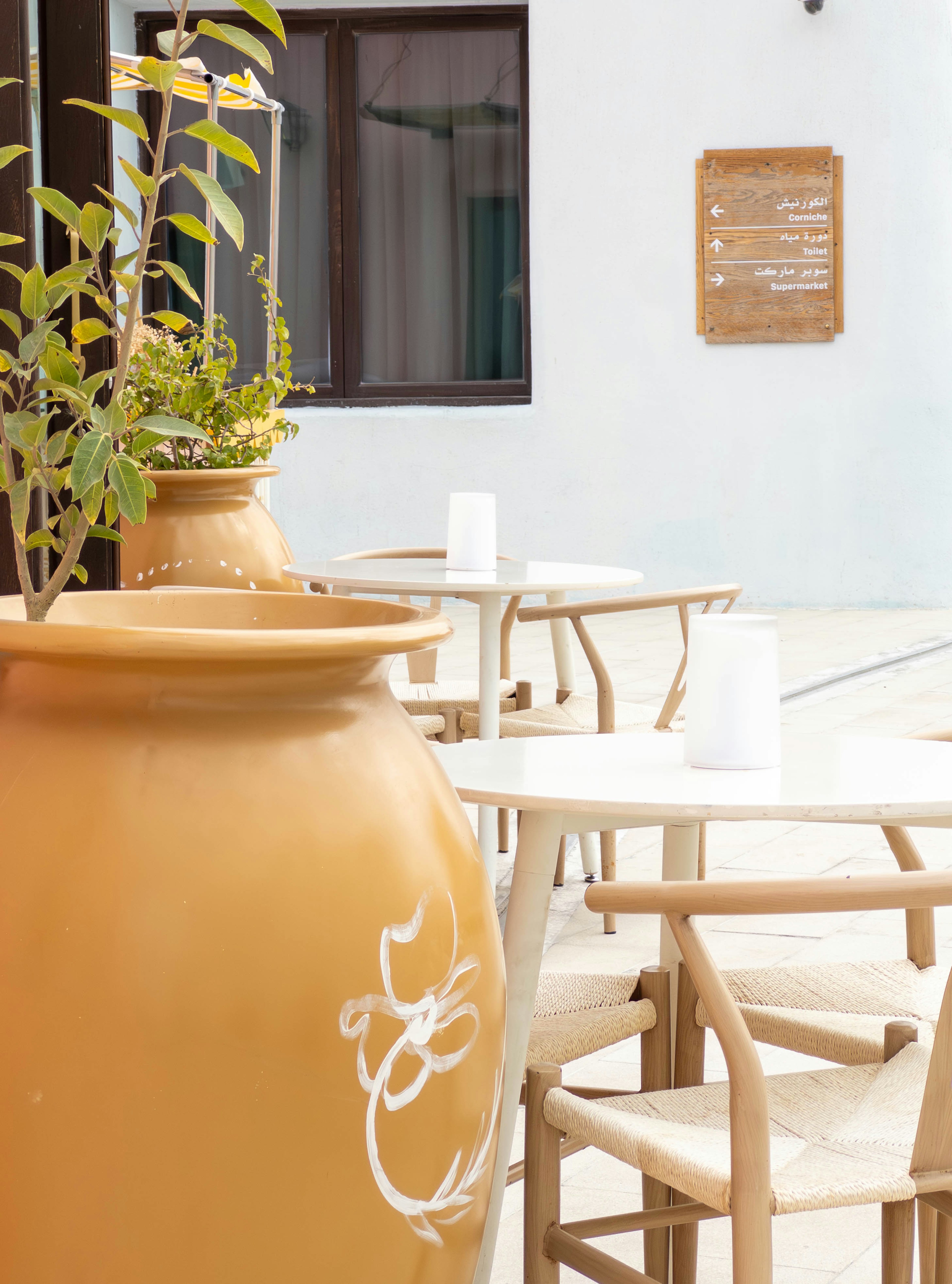 Scène de café avec un grand pot jaune et des chaises en bois