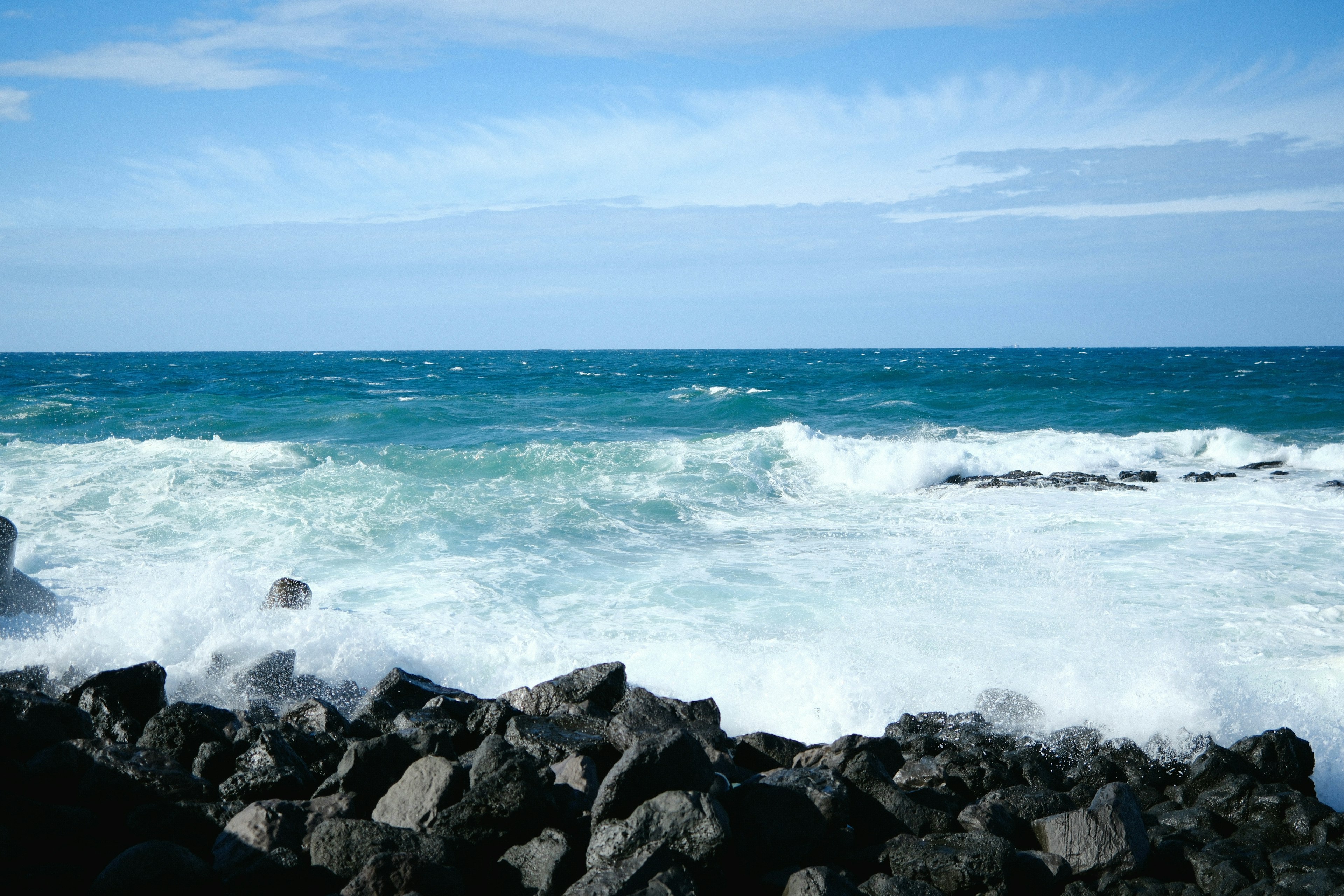 Scenic view of blue ocean waves crashing against rocky shore