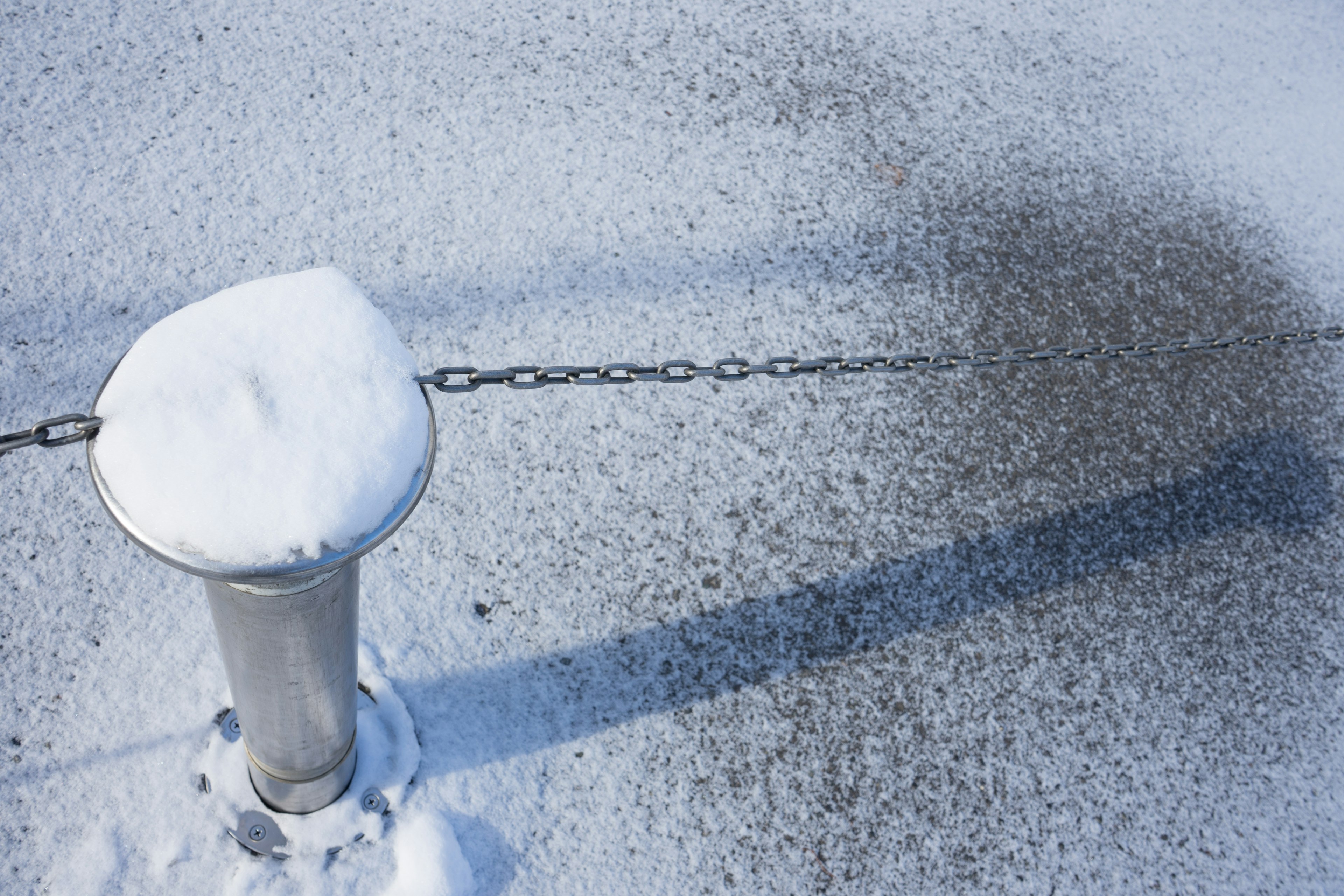 Palo coperto di neve con catena e ombra