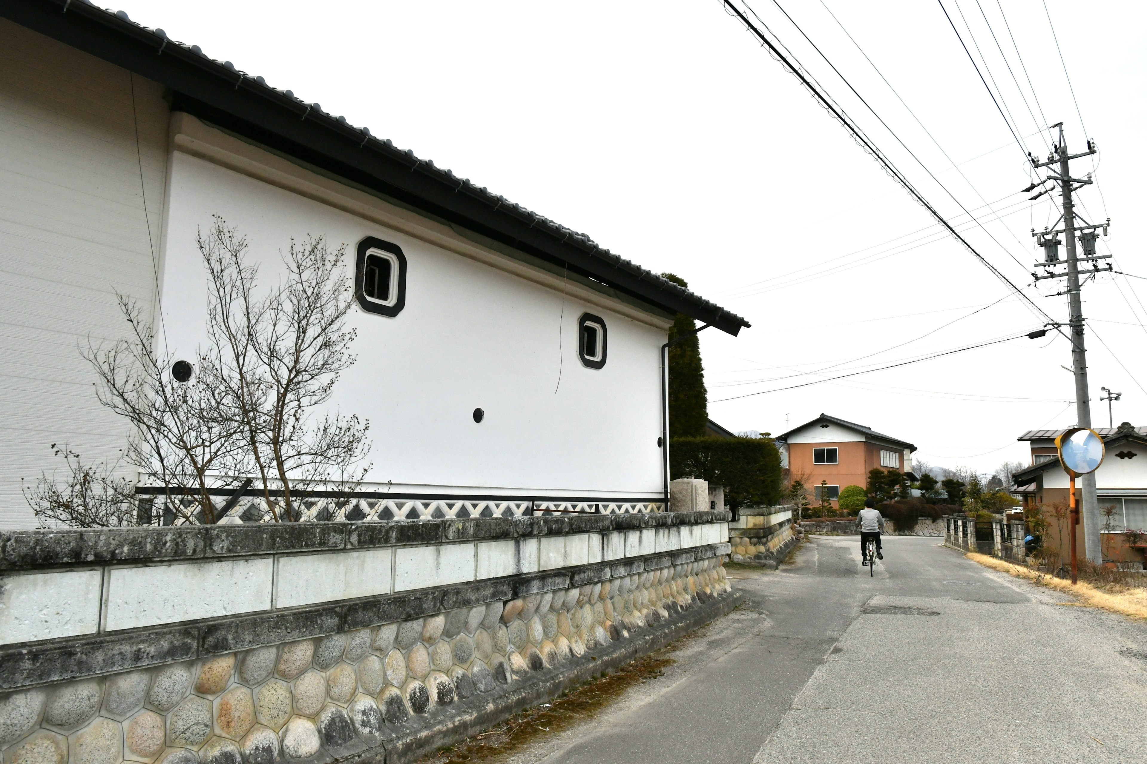 Traditionelles Gebäude mit weißen Wänden und Steinmauer entlang der Straße