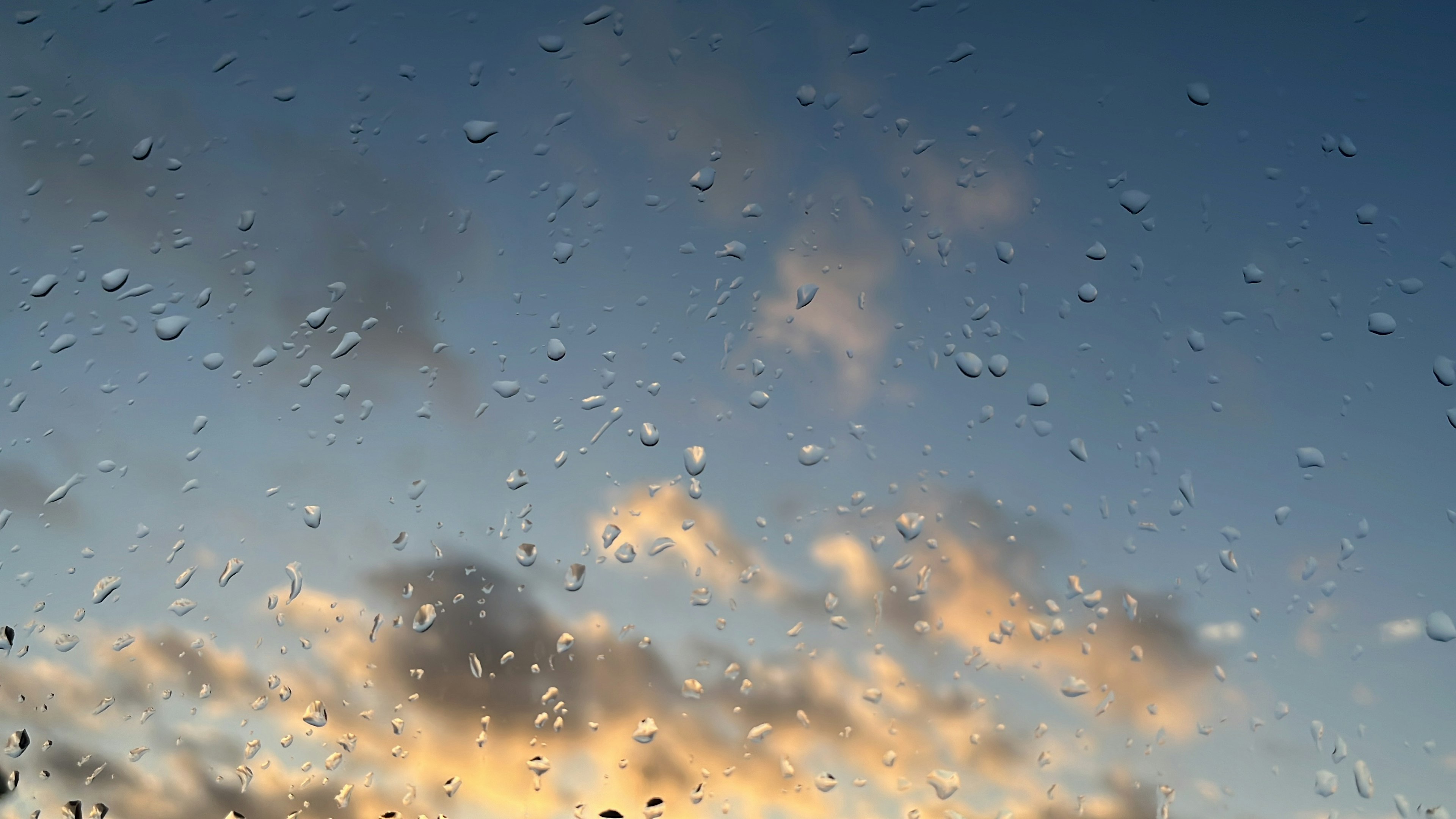 Cielo al atardecer con gotas de lluvia en la ventana