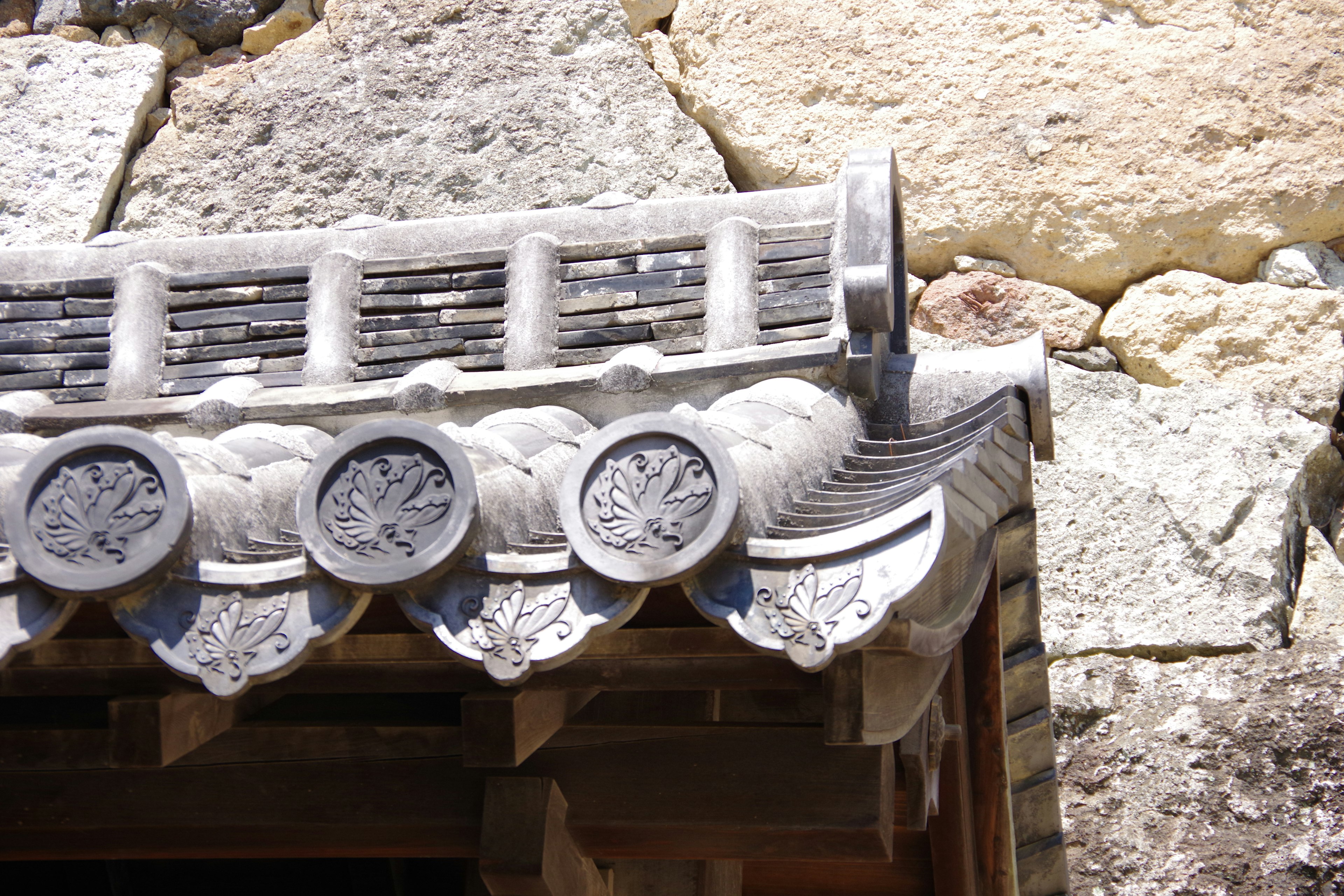 Traditional Japanese roof detail with stone wall