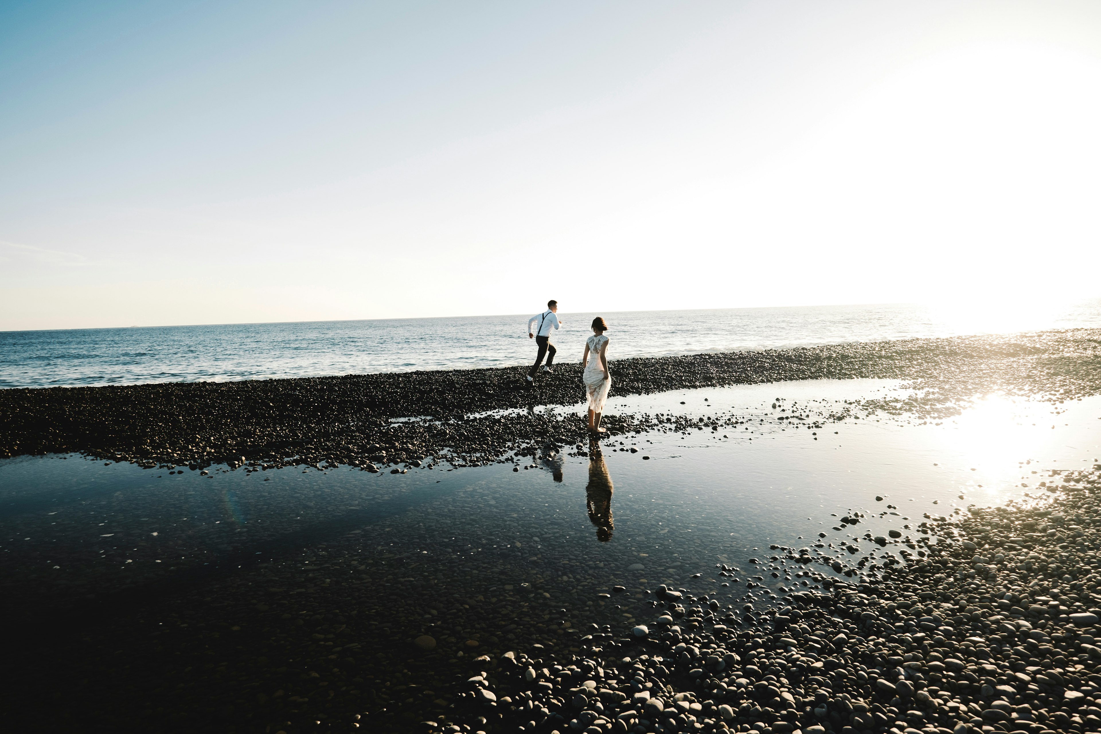 Silhouette of a couple walking by the beach with reflections on the water