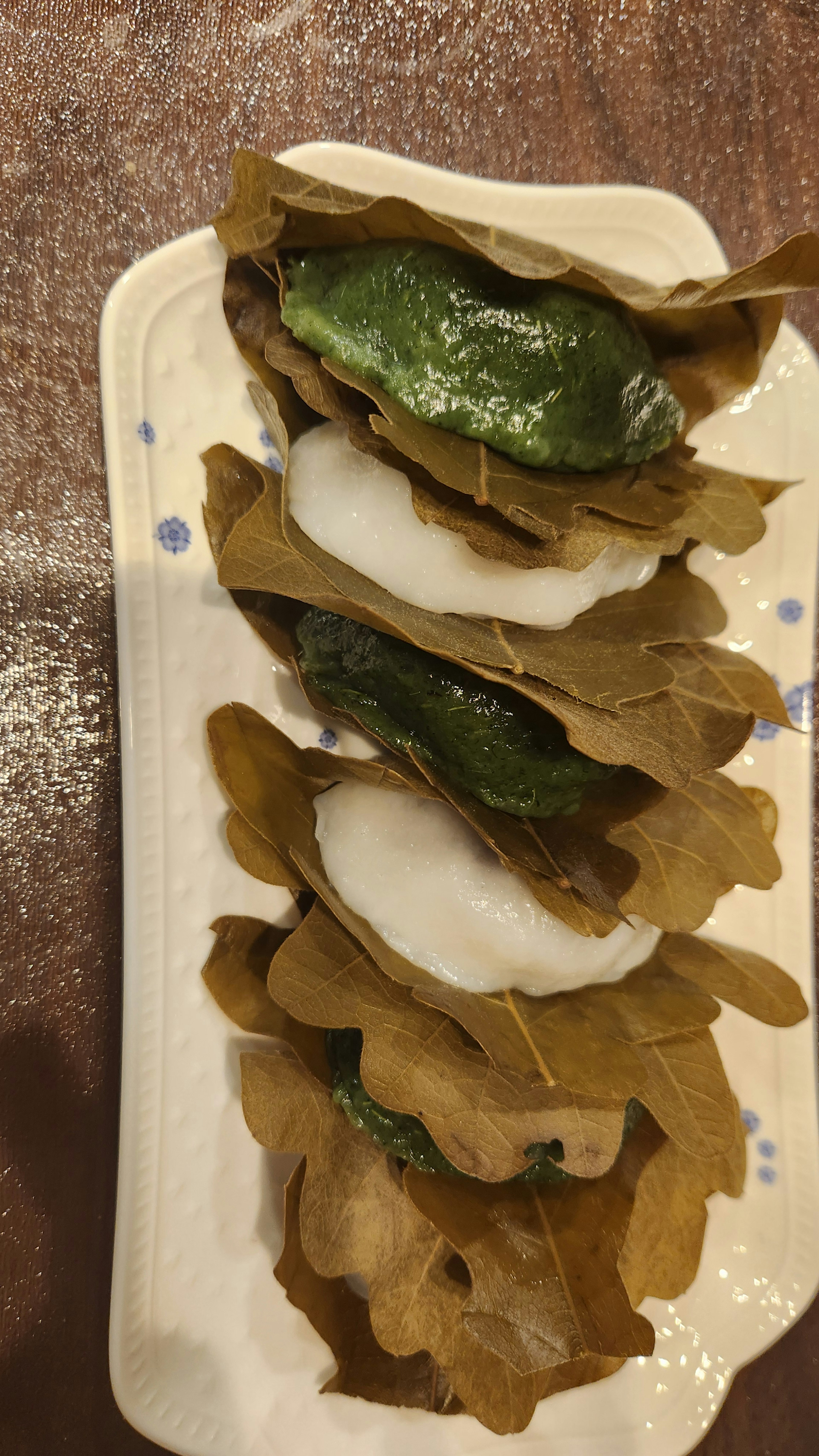 A plate of green leaf-wrapped delicacies arranged neatly