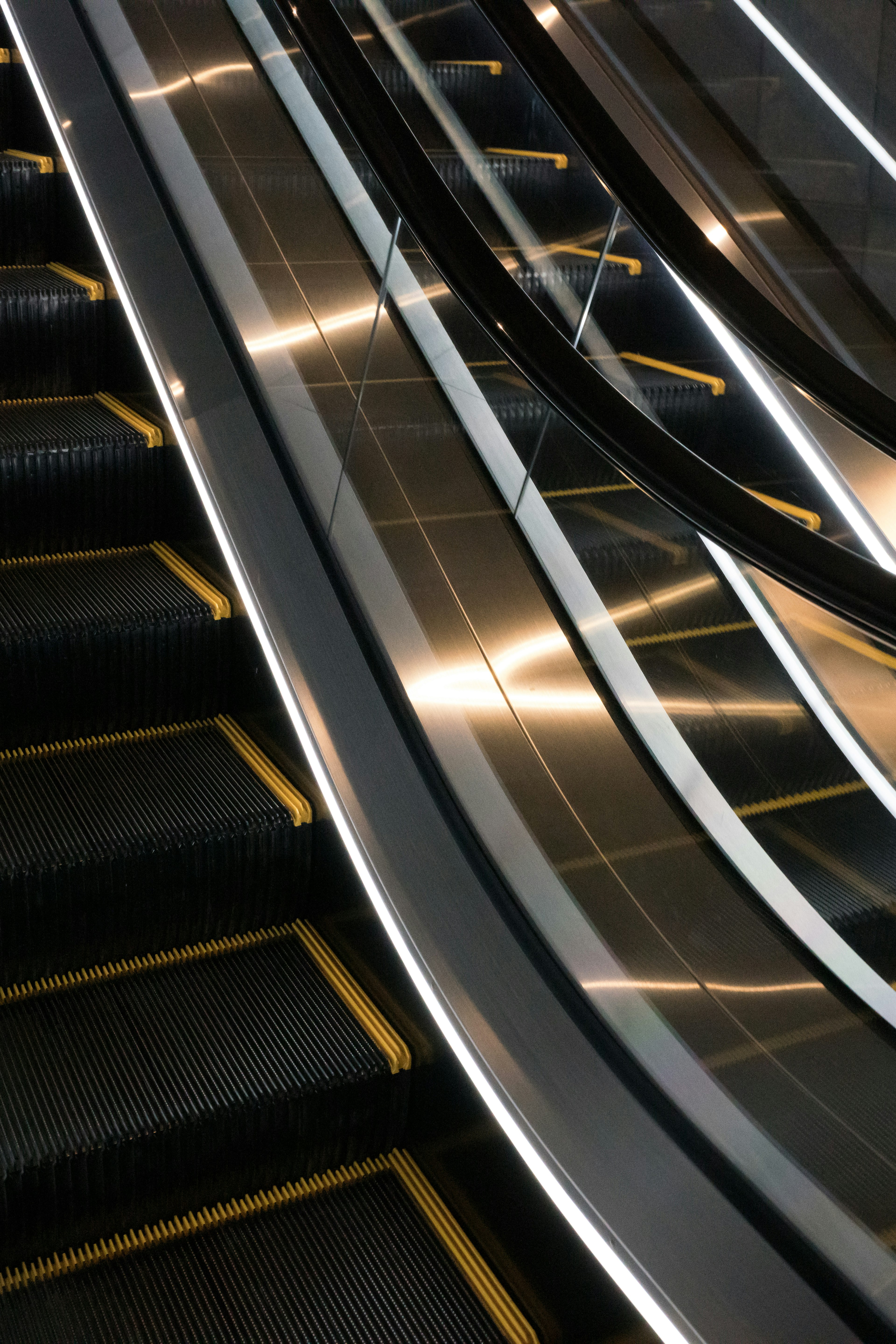 Curvas suaves y superficie brillante de una escalera mecánica negra y dorada