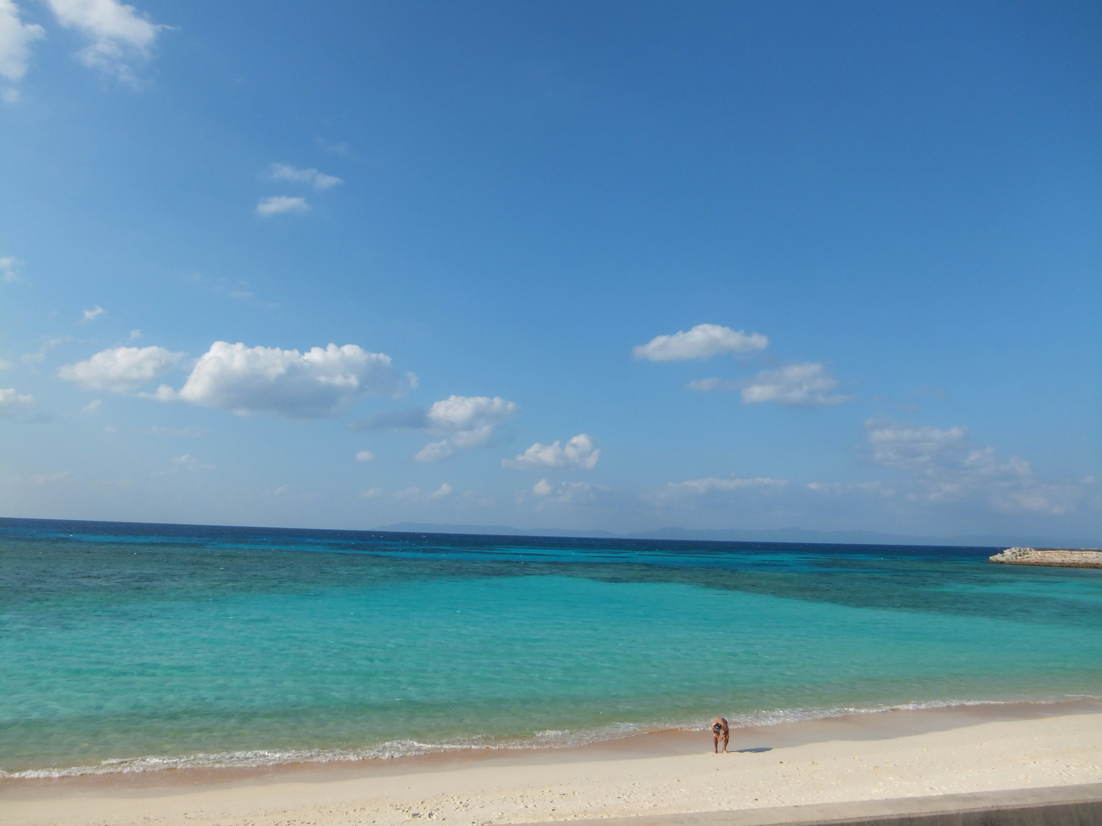 Malersicher Strand mit blauem Ozean und weißem Sand mit einer einsamen Figur