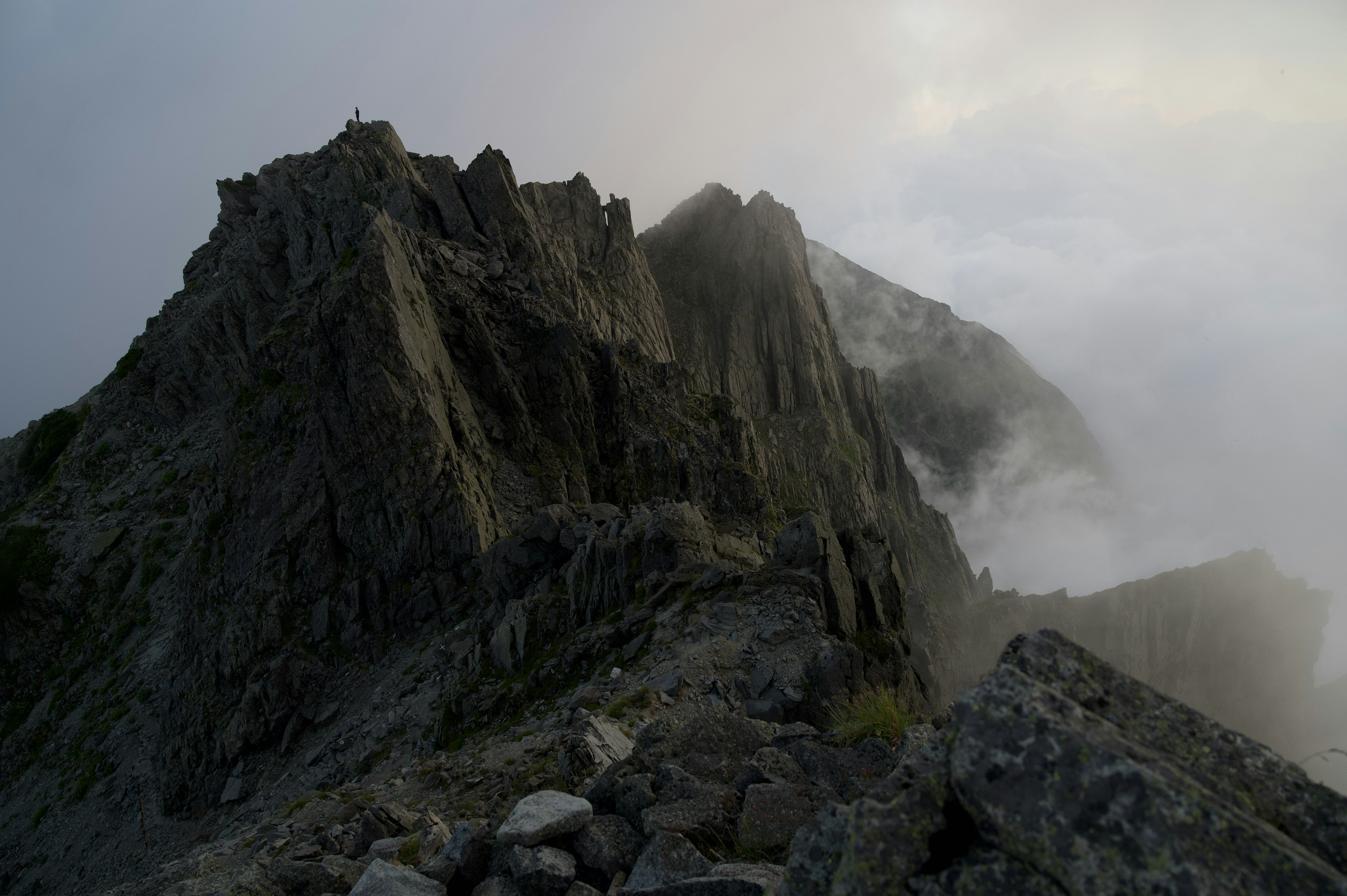 A mountain landscape enveloped in mist featuring striking jagged rock formations