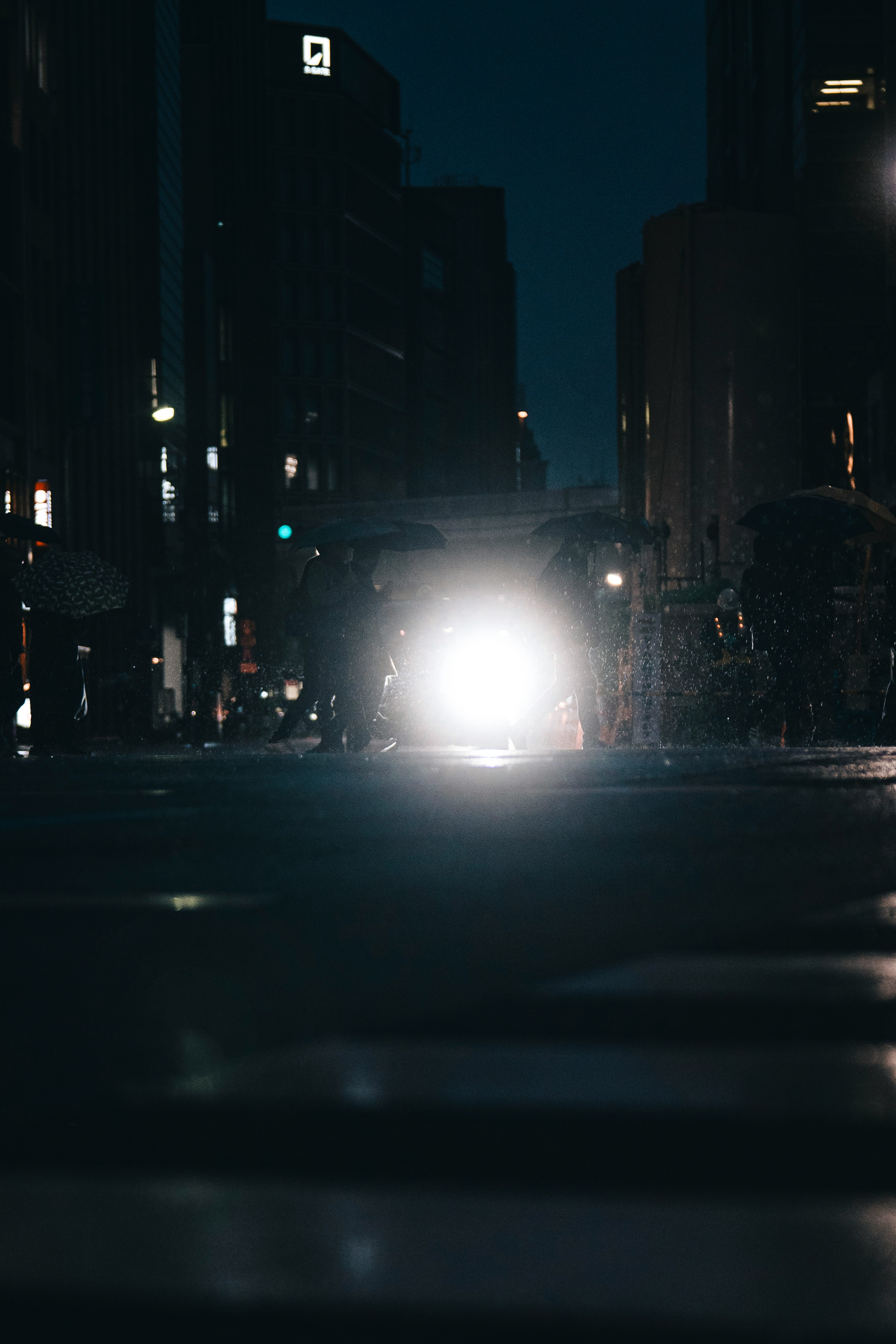 Escena de un faro de coche brillando en una intersección de la ciudad de noche