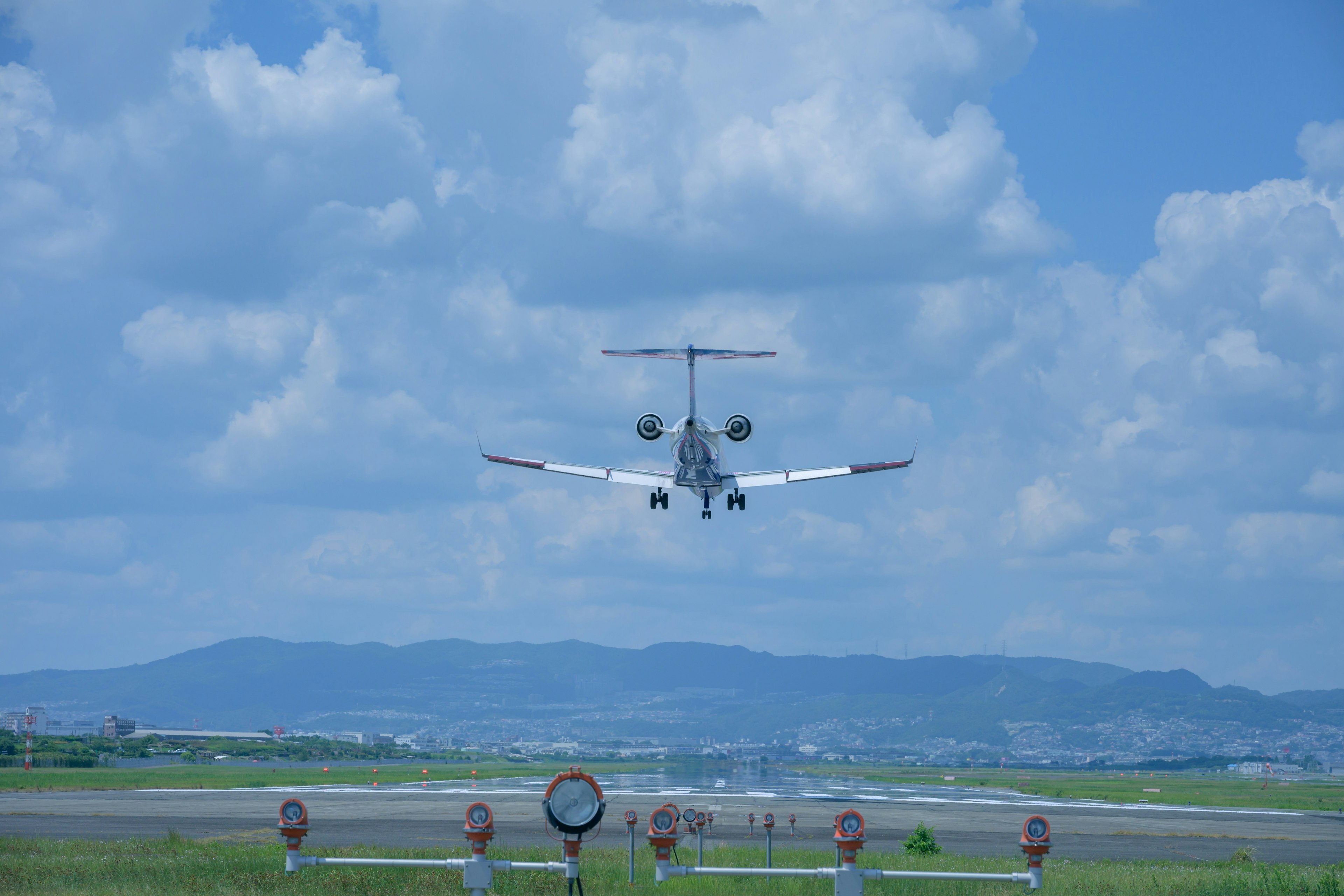 Kleinflugzeug landet vor blauem Himmel und grünem Rollfeld