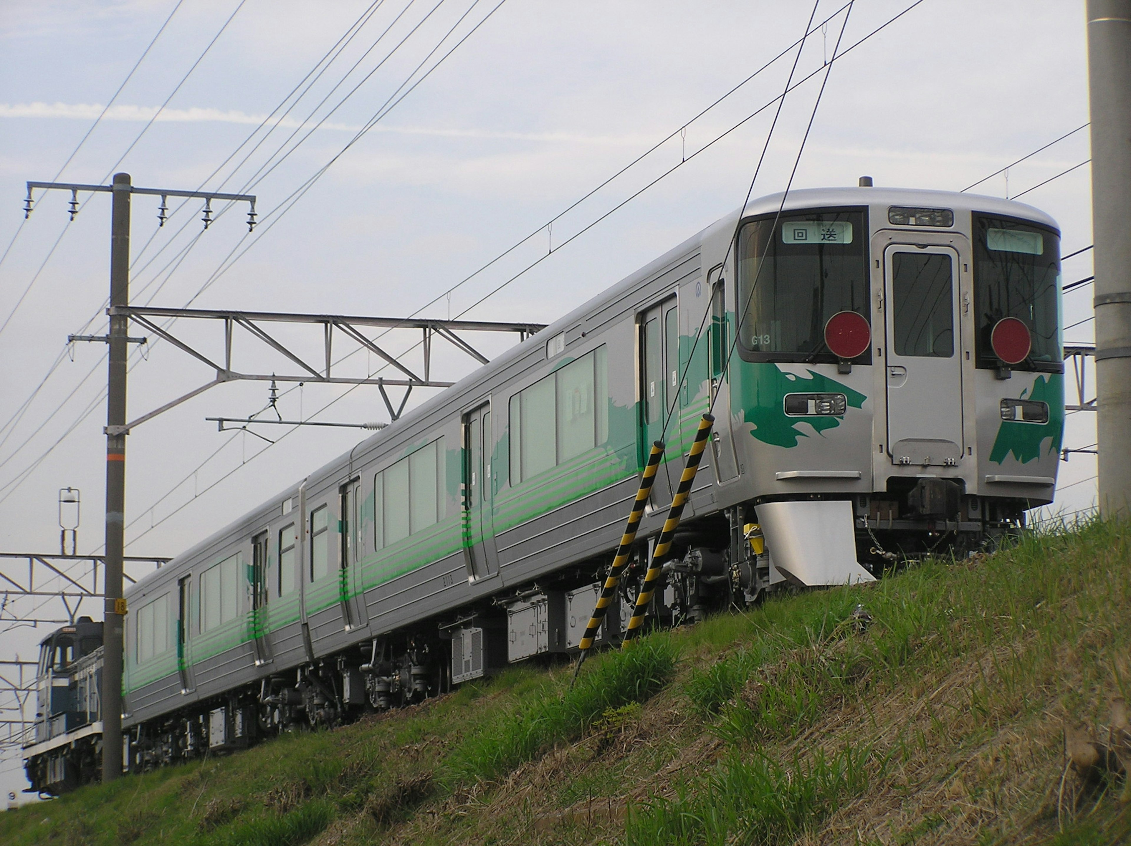 A green-themed train parked beside the railway tracks