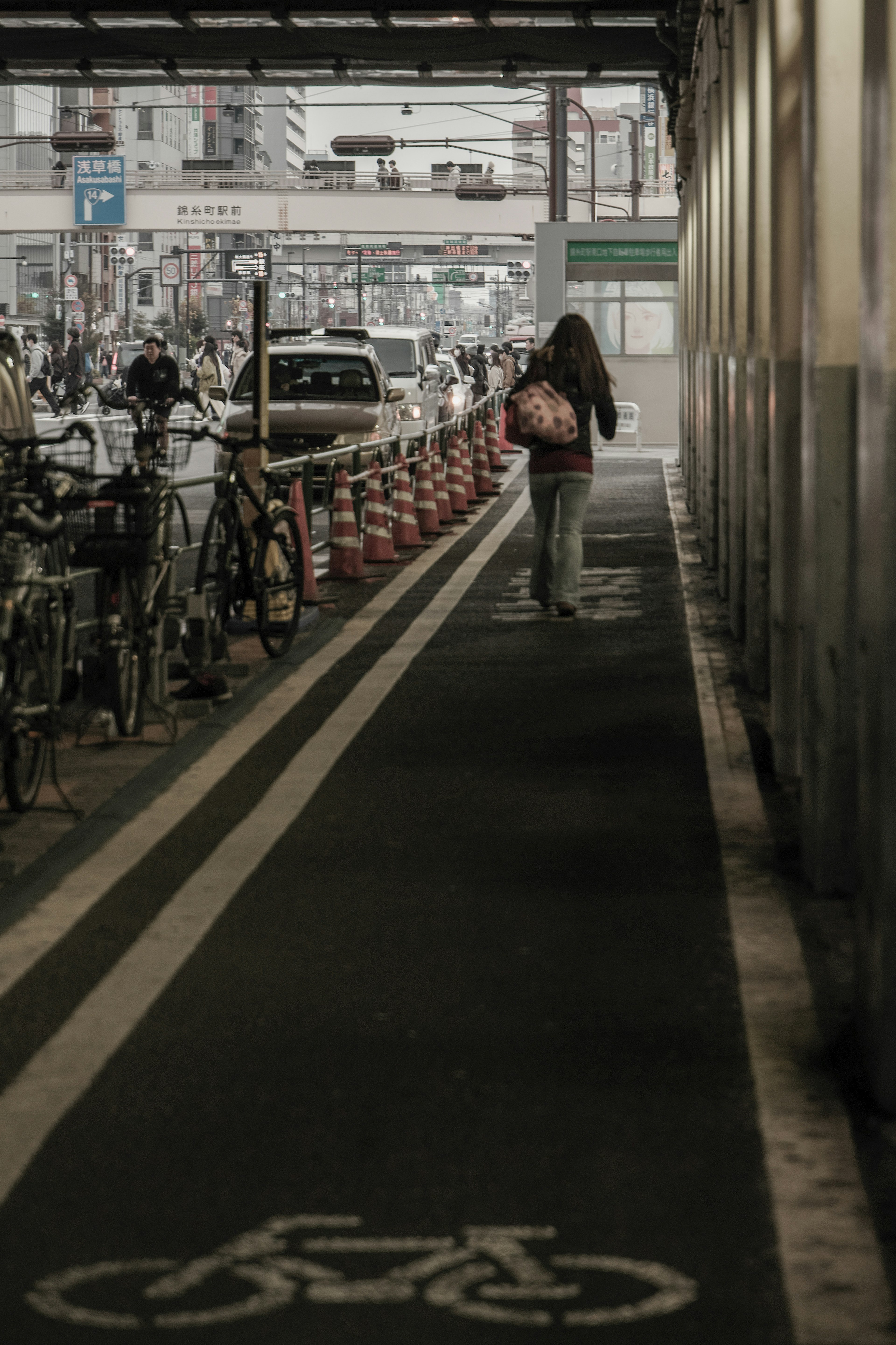 A woman walking on a bicycle path next to parked bikes in a city street