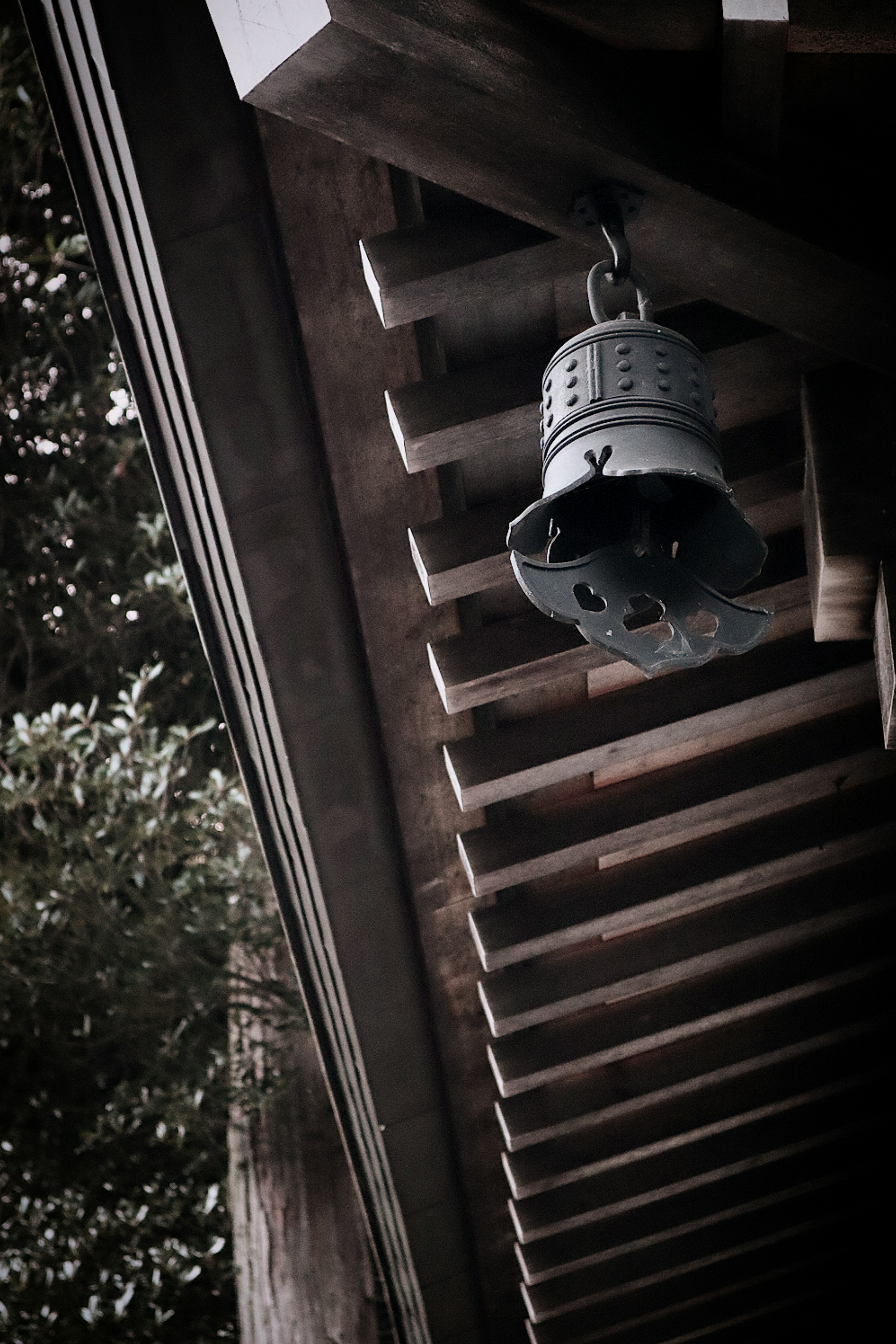 Image d'une vieille cloche suspendue sous un toit en bois