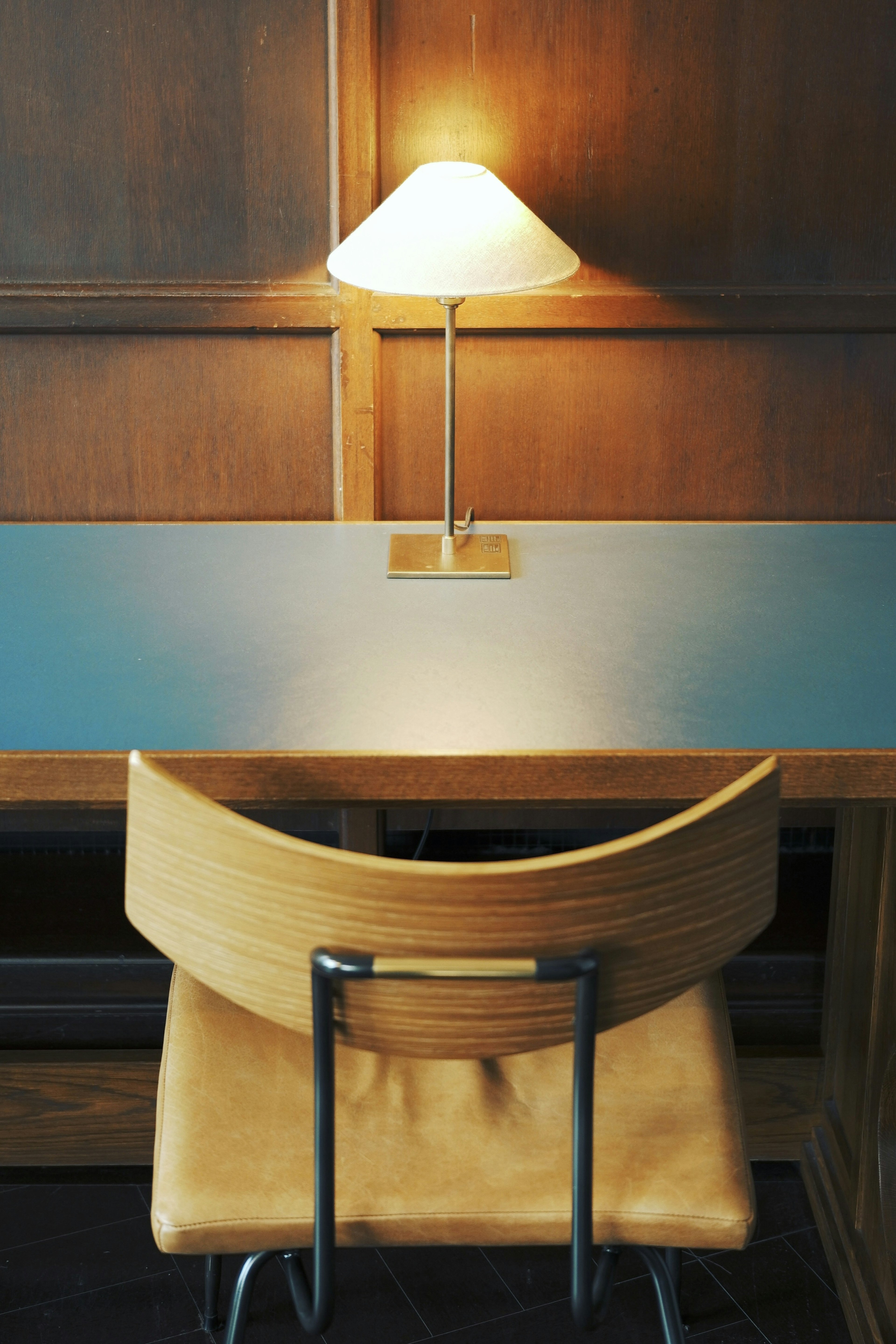 A leather chair with a unique design in a room featuring wooden walls and a blue background with a lamp