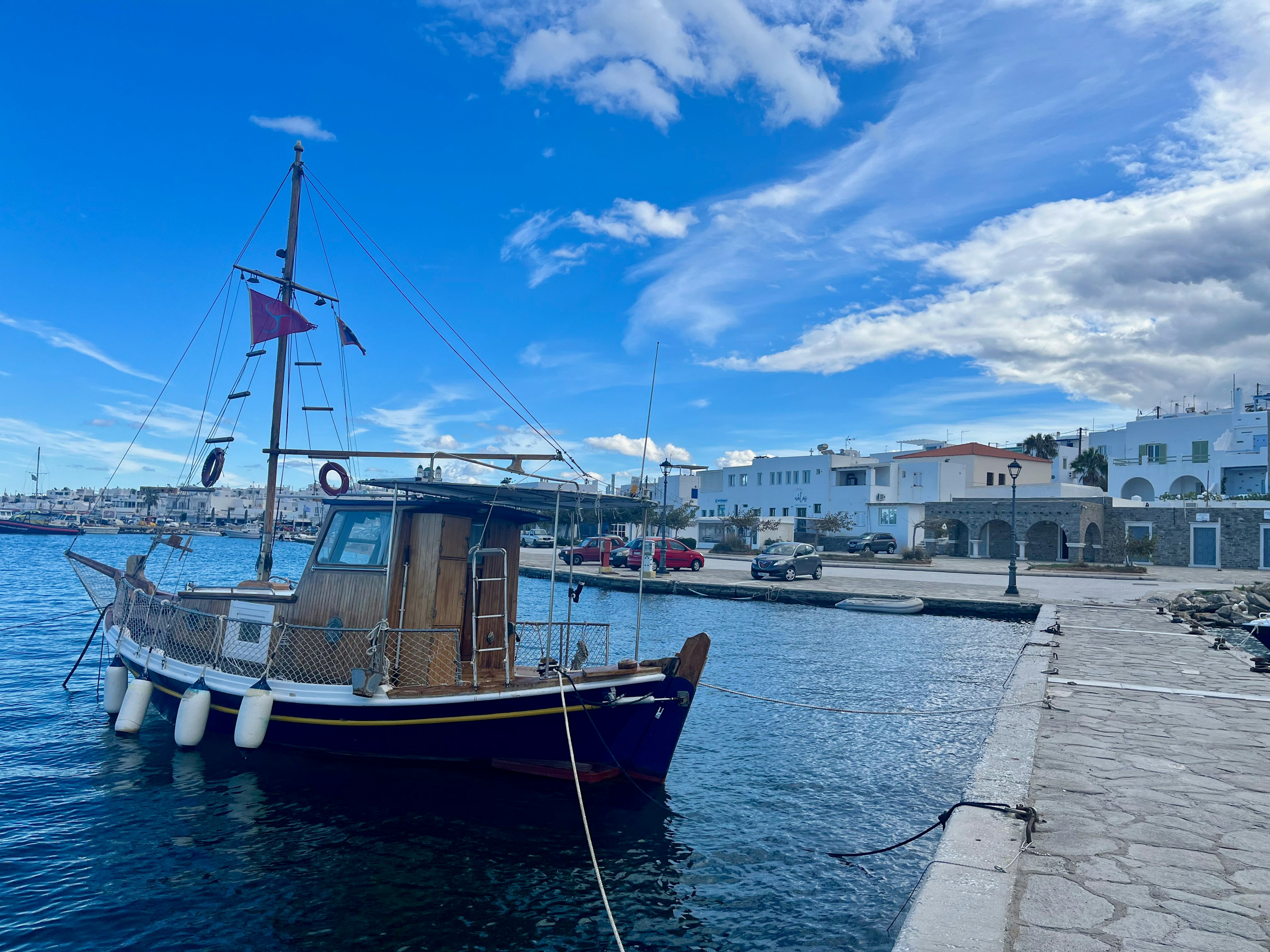 Ein kleines Fischerboot im Hafen mit blauem Himmel und weißen Wolken