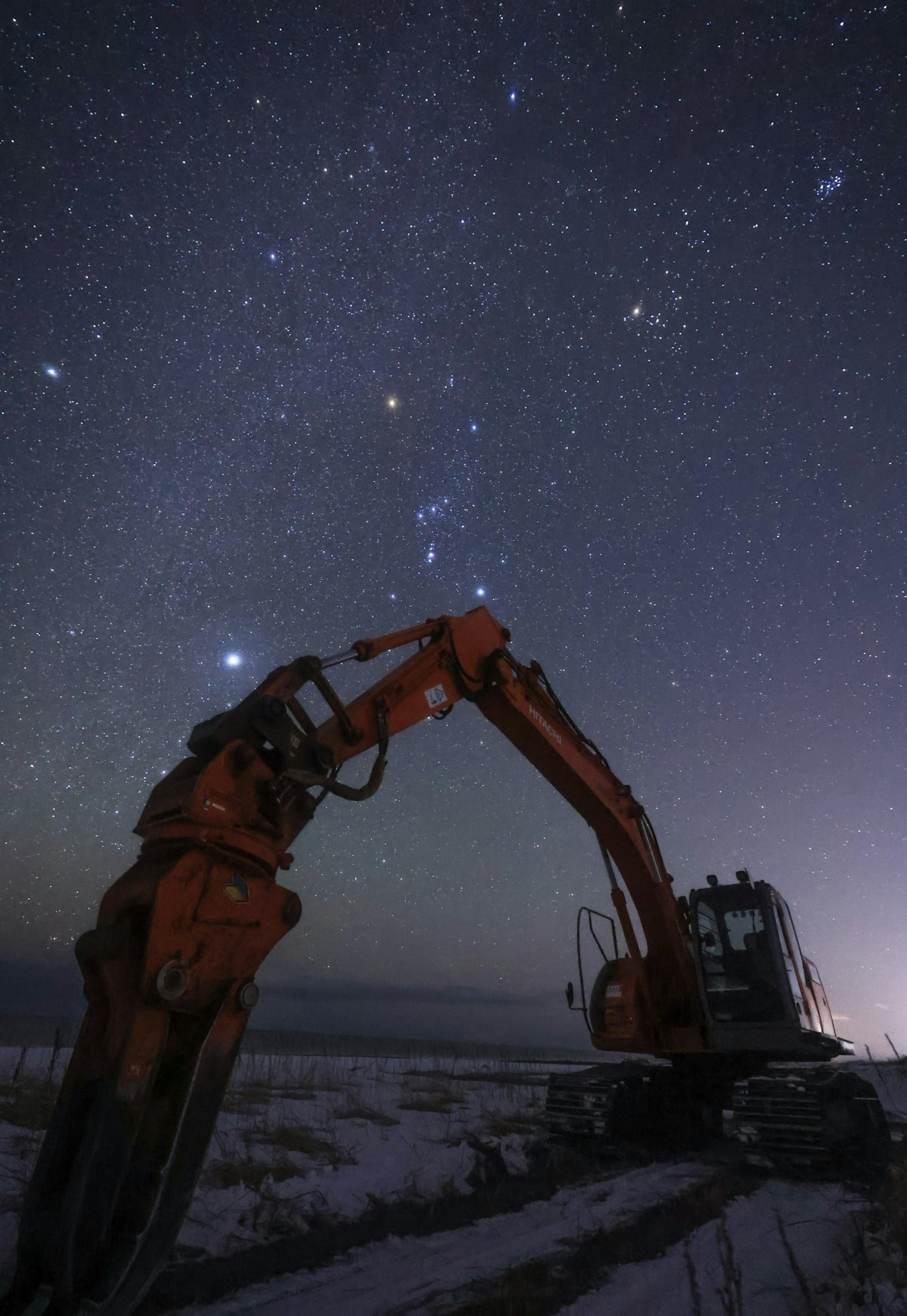 夜空に星々が輝く中、重機のクレーンが映える風景