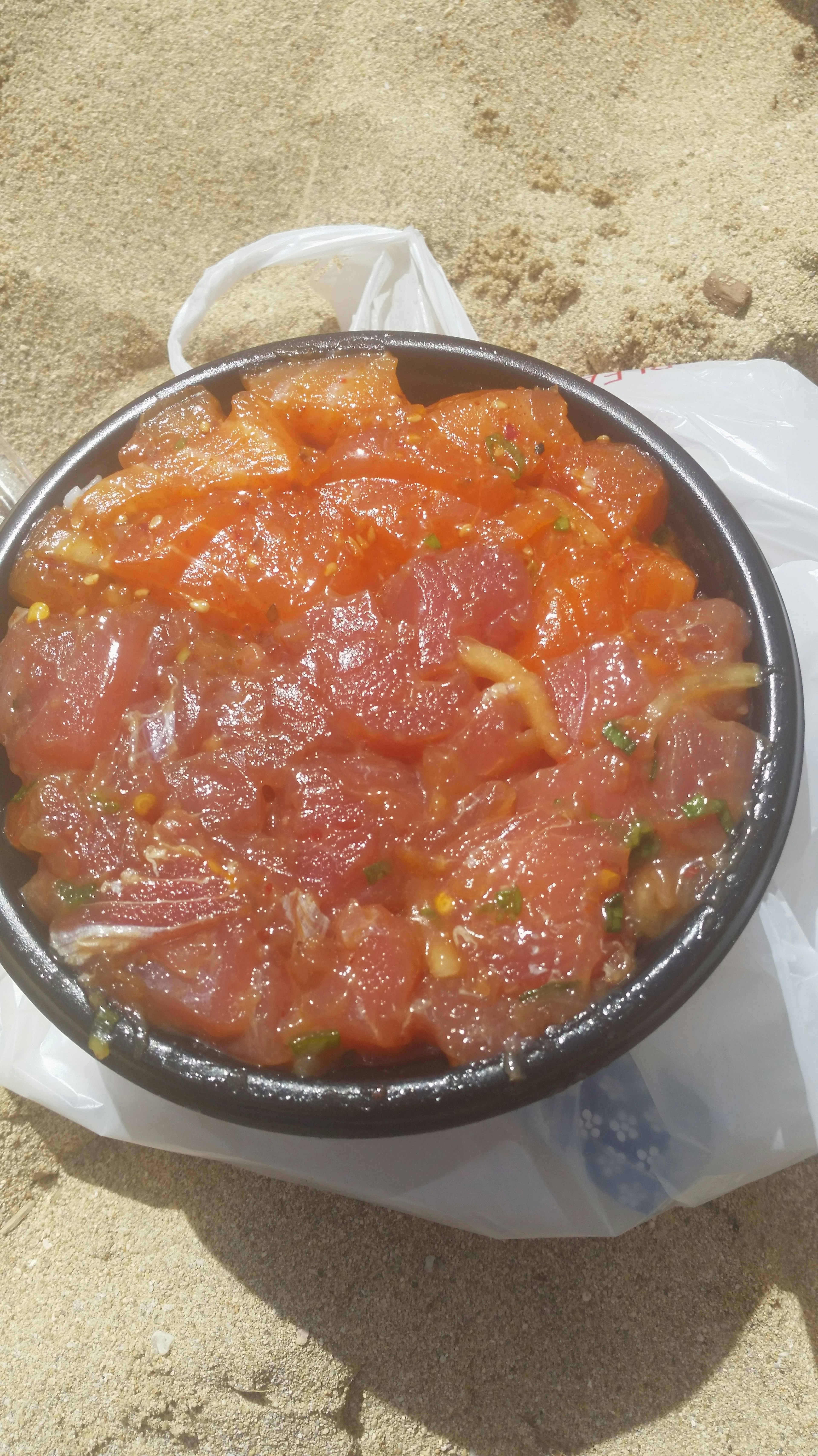 Un tazón de sashimi de atún fresco colocado en la playa