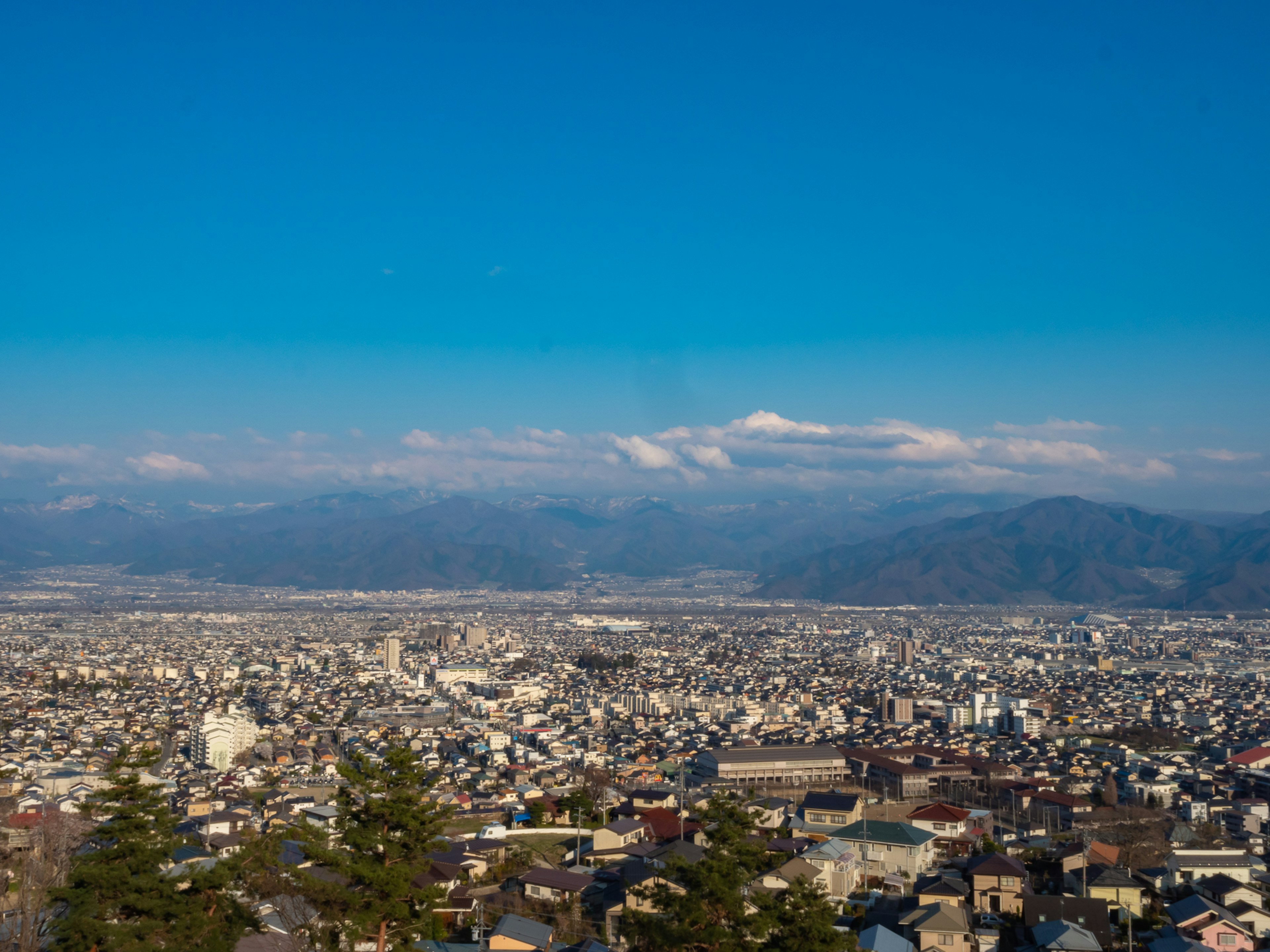 Expansive cityscape from a mountain with clear blue sky