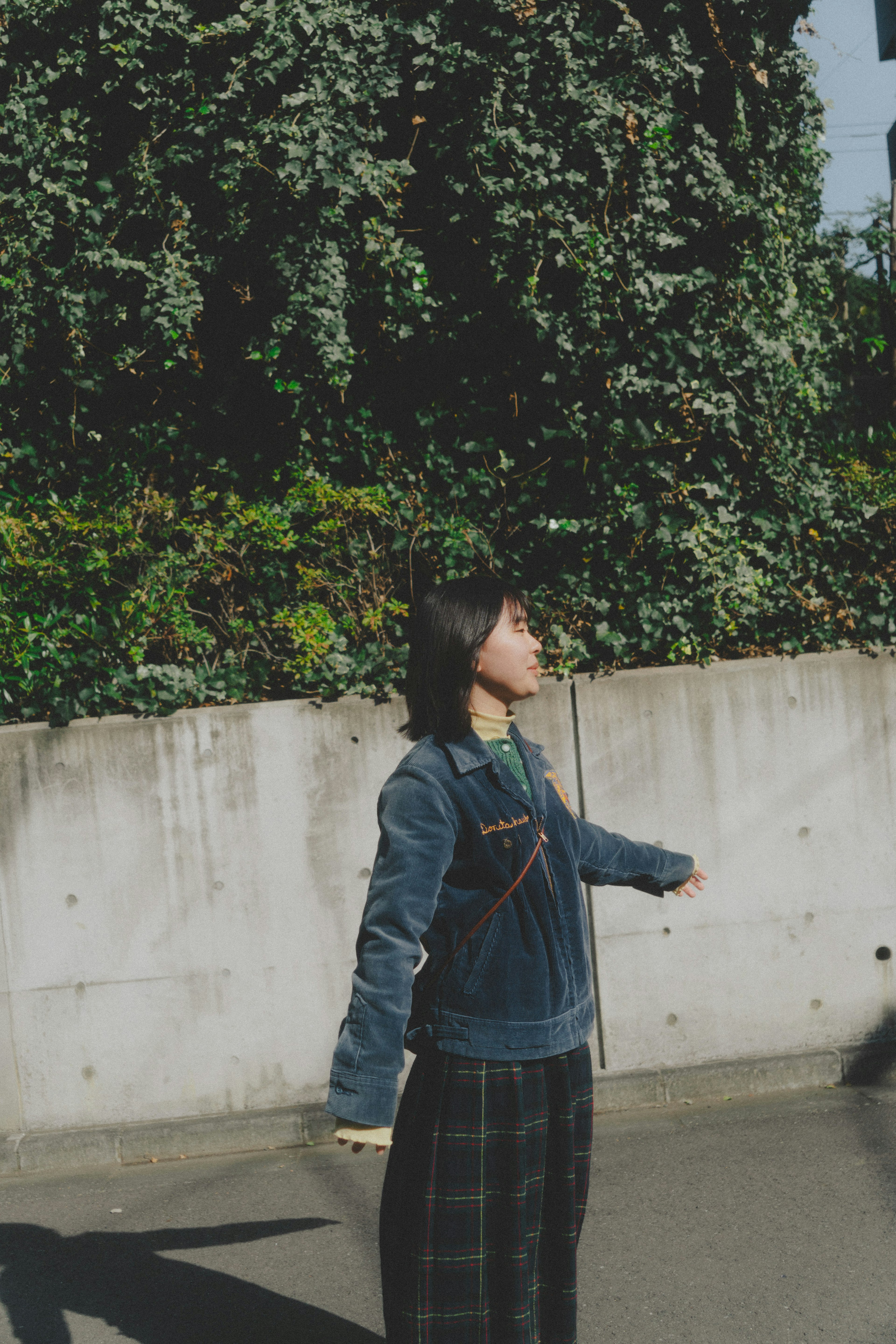 A woman standing with arms outstretched against a green background