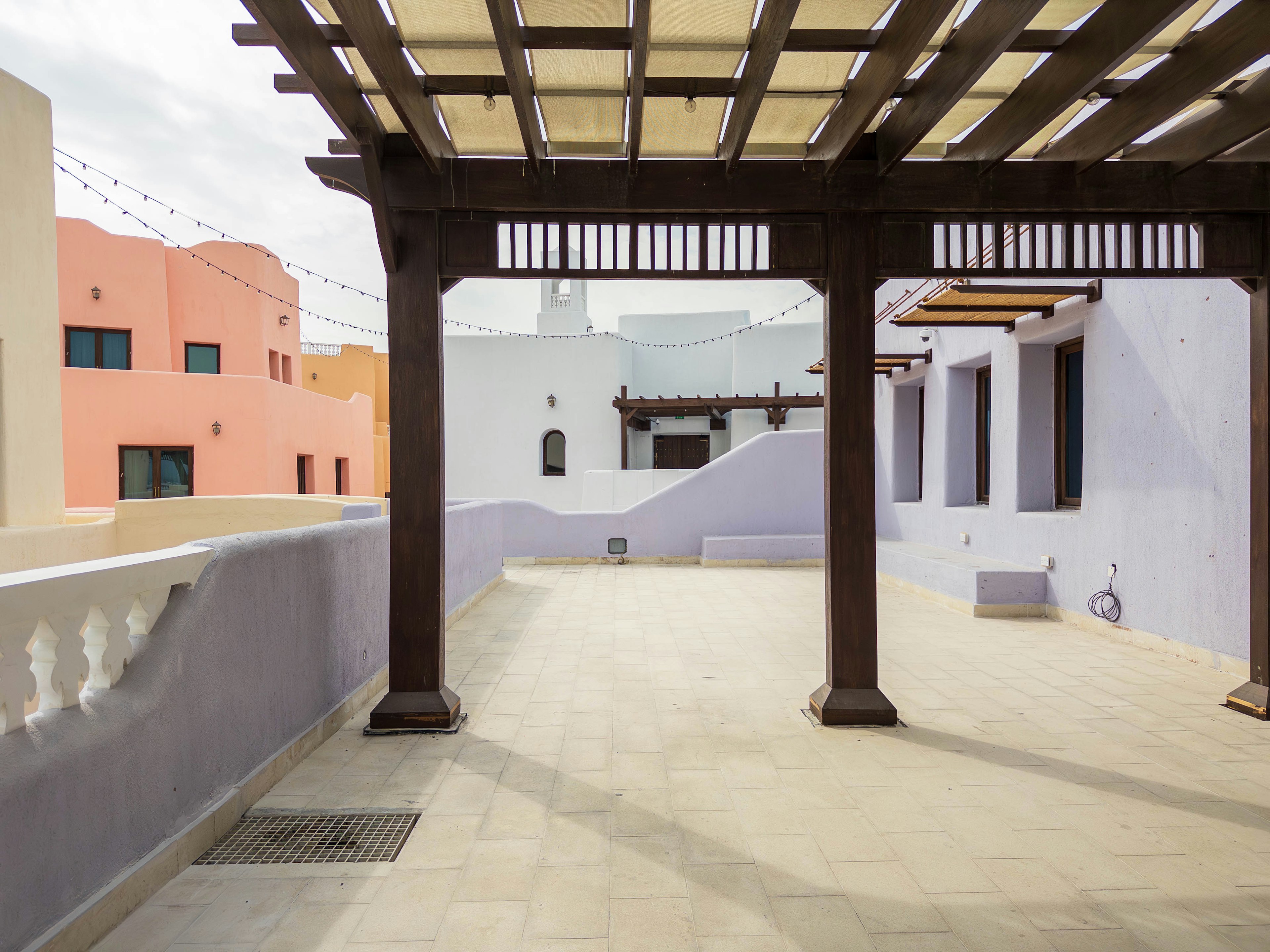 Terraza espaciosa con pérgola de madera y edificios coloridos