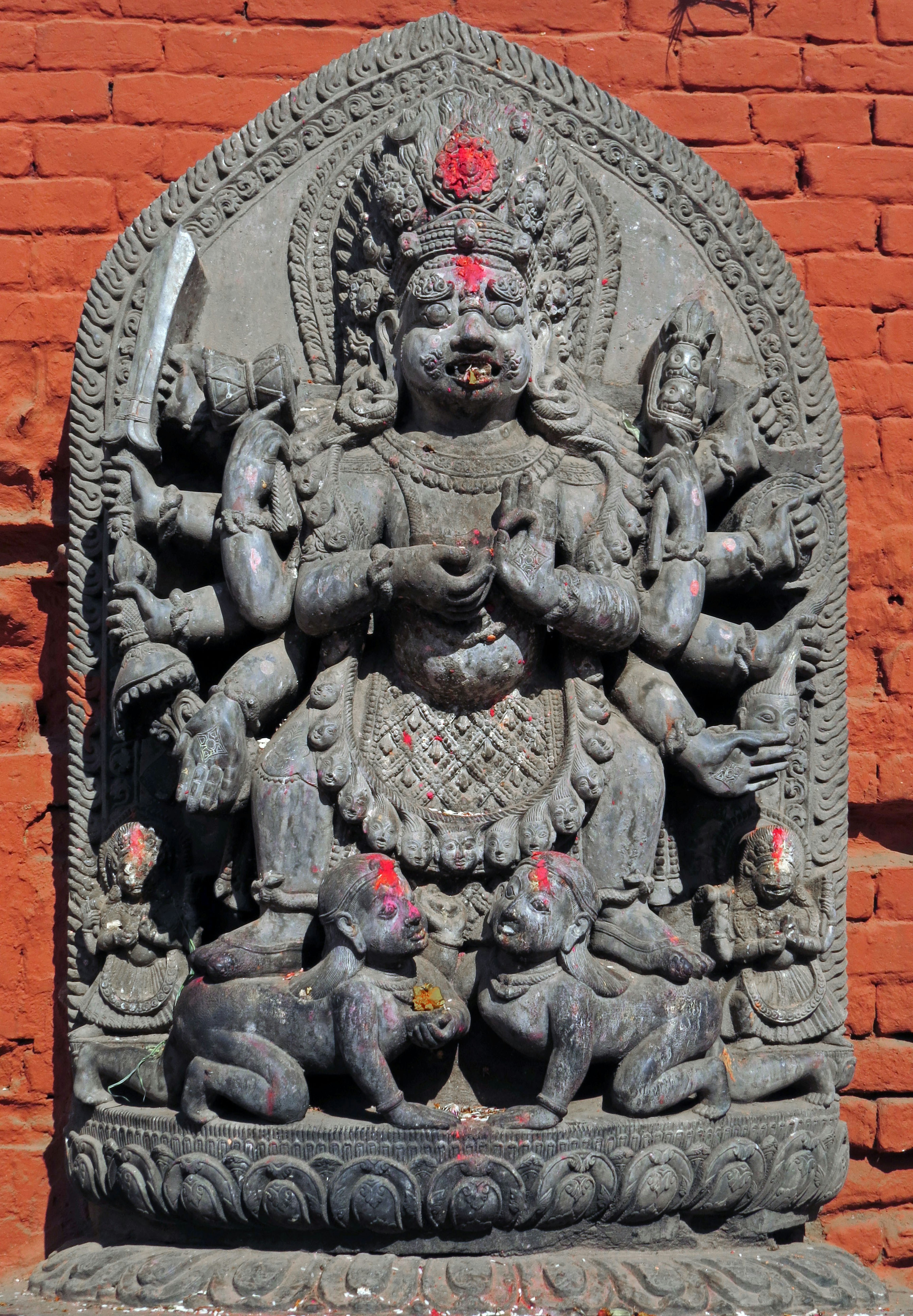 A multi-armed deity statue stands in front of two animals