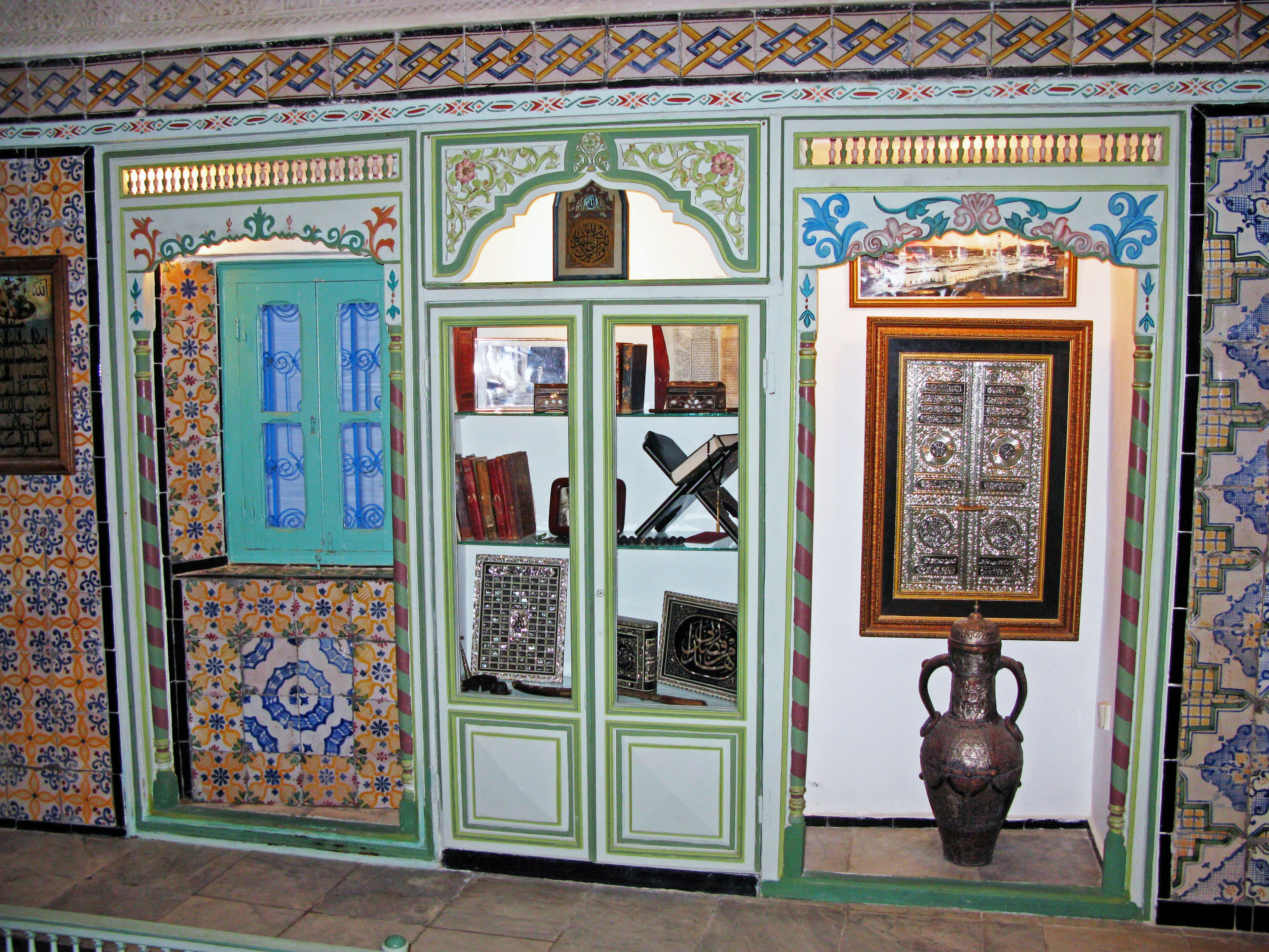 Intérieur traditionnel marocain avec décor orné porte verte fenêtres bleues et carreaux décoratifs