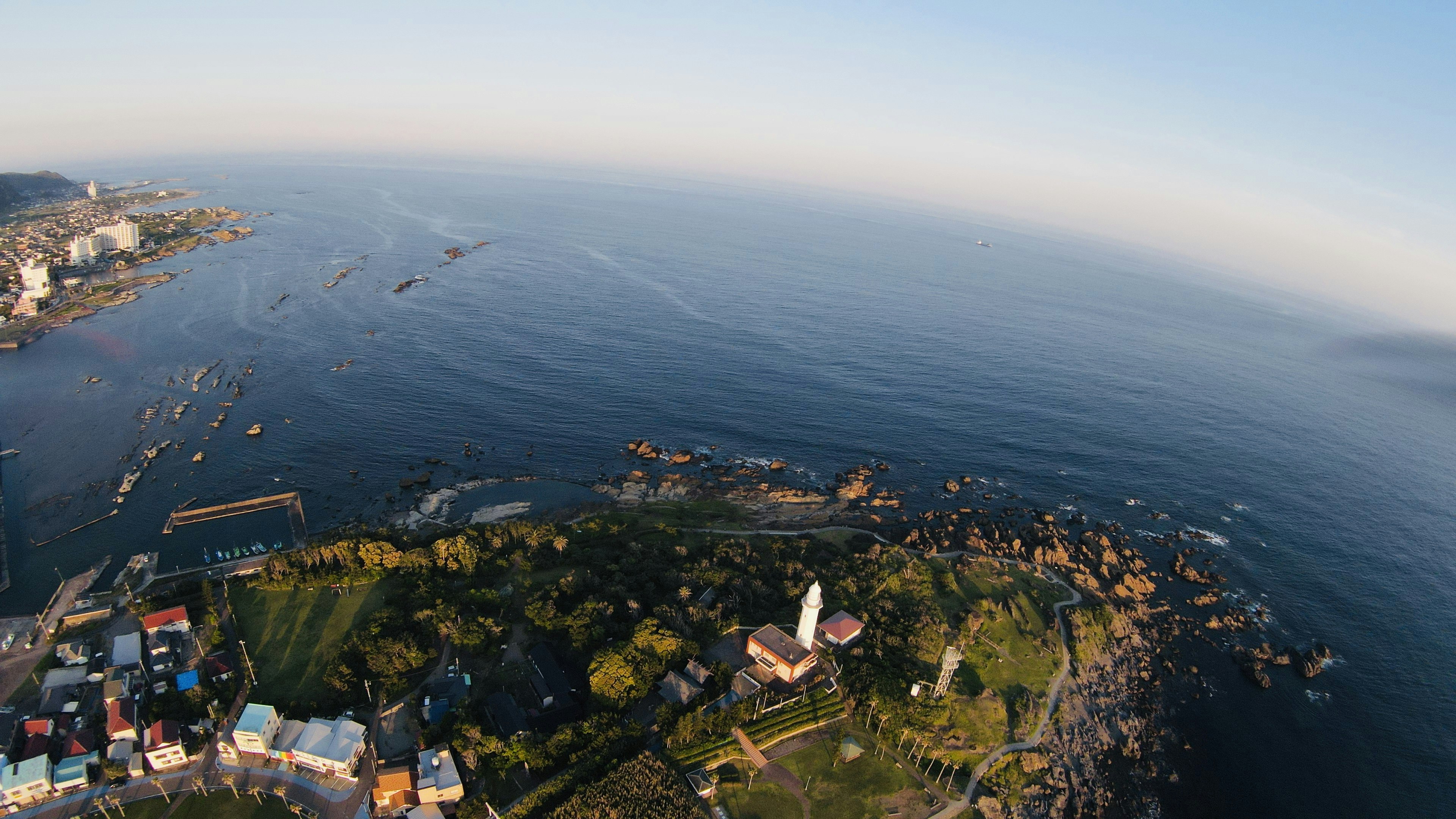 Vista aérea de una zona costera con un faro y barcos en el agua