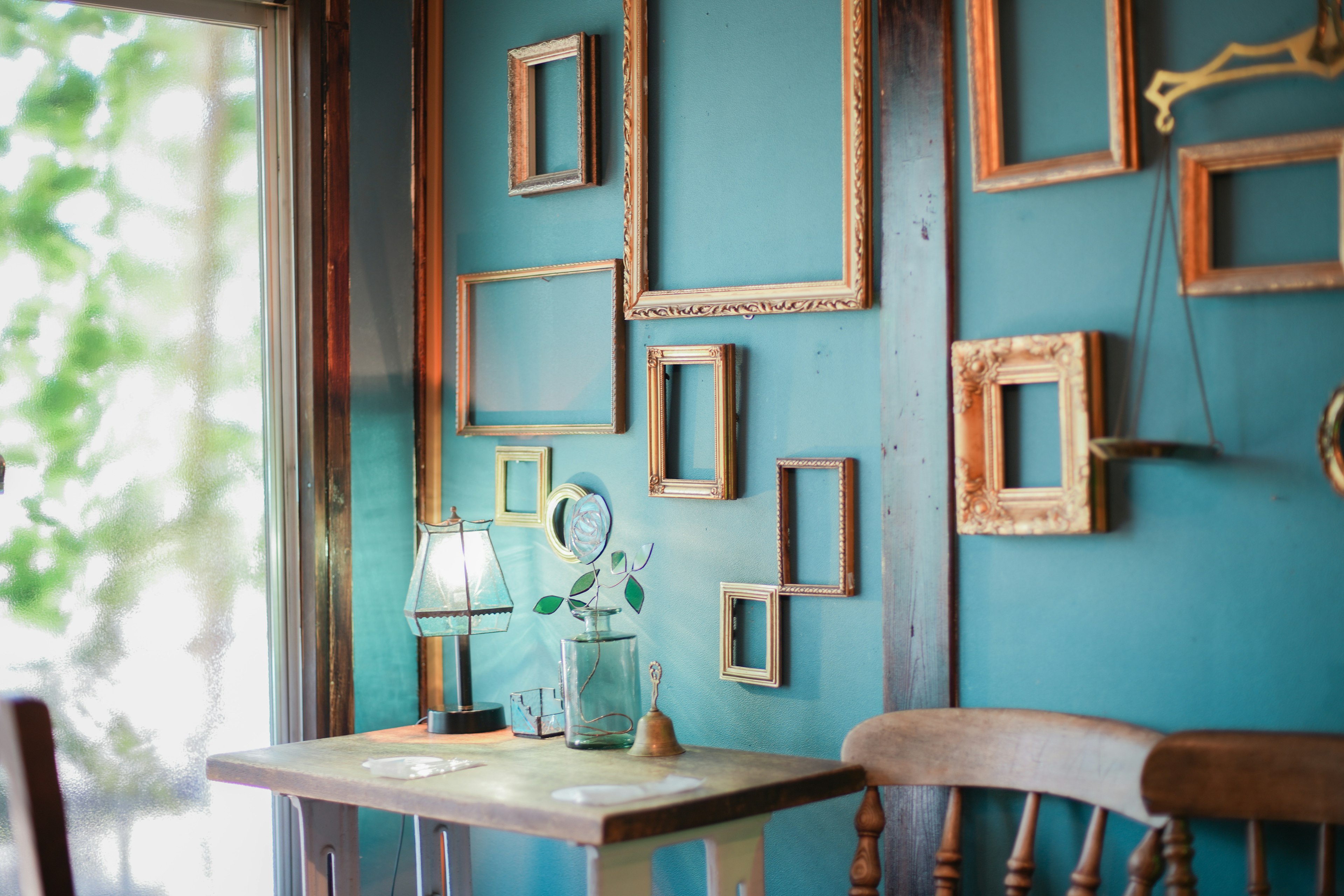 A corner of a room with wooden picture frames arranged irregularly on a blue wall