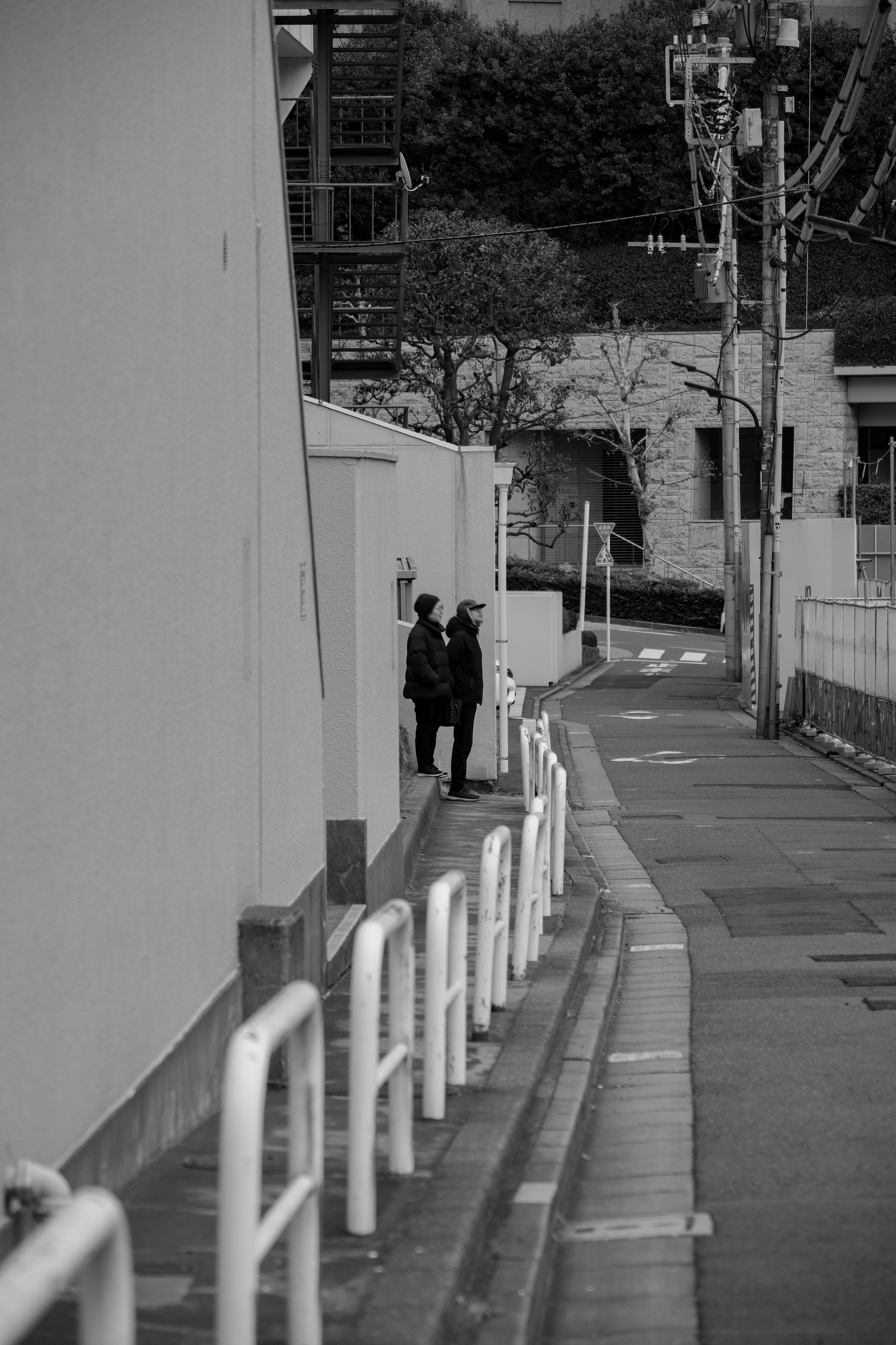 Deux figures se tenant dans une ruelle étroite avec une clôture blanche dans un cadre monochrome