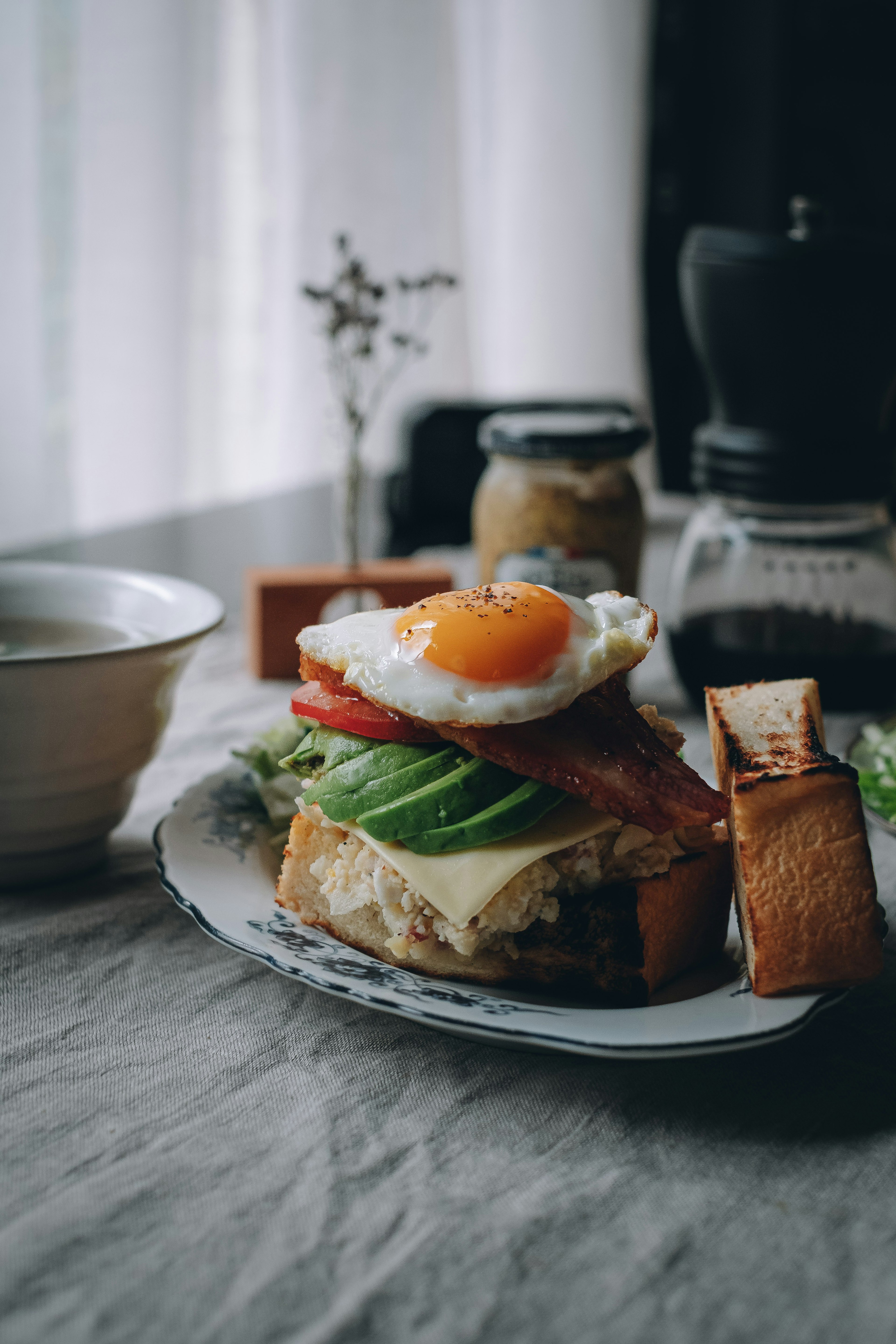 Foto makanan yang menampilkan roti panggang dengan telur mata sapi, selada, dan tomat