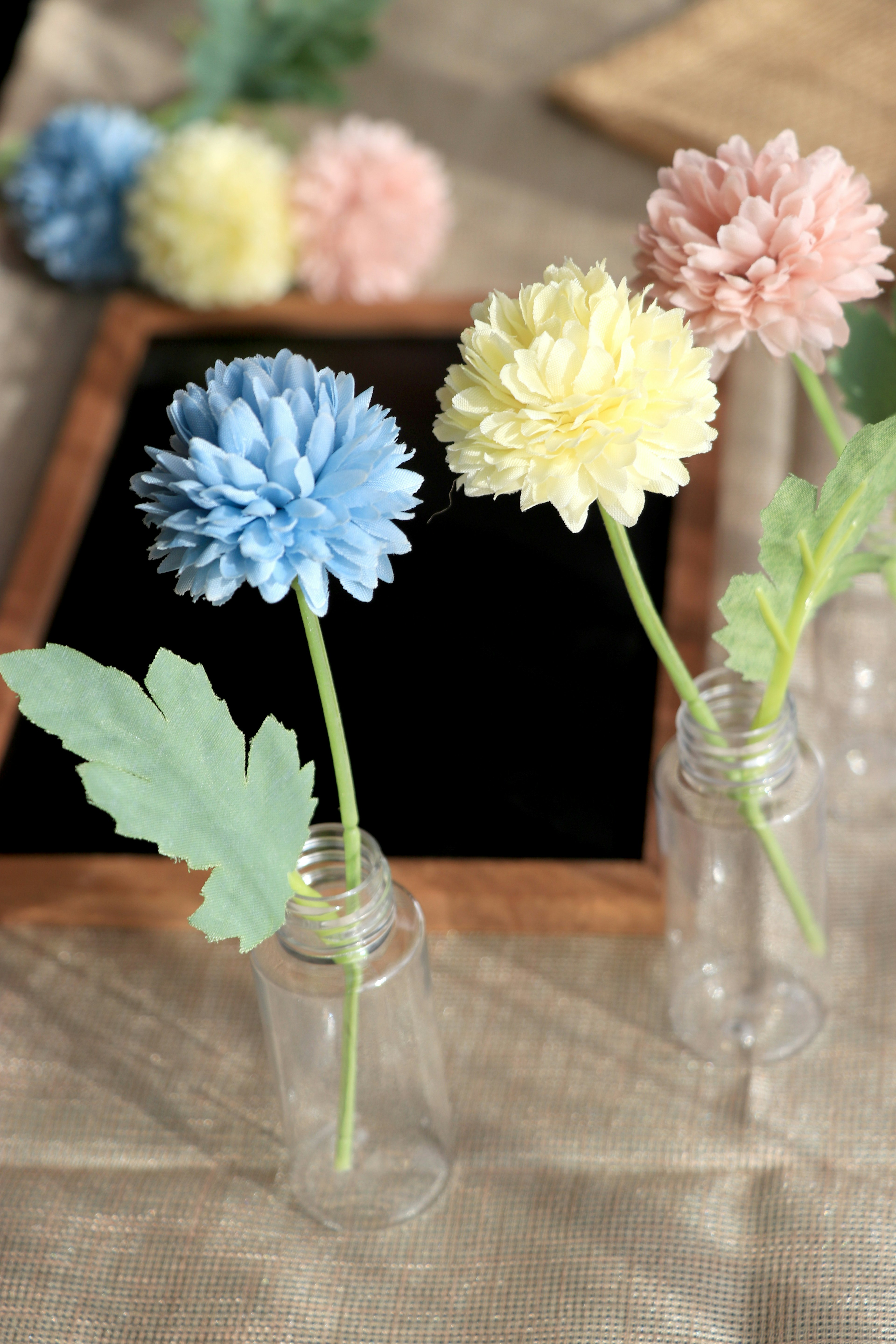 Fleurs colorées bleues, jaunes et roses disposées dans des bouteilles en verre