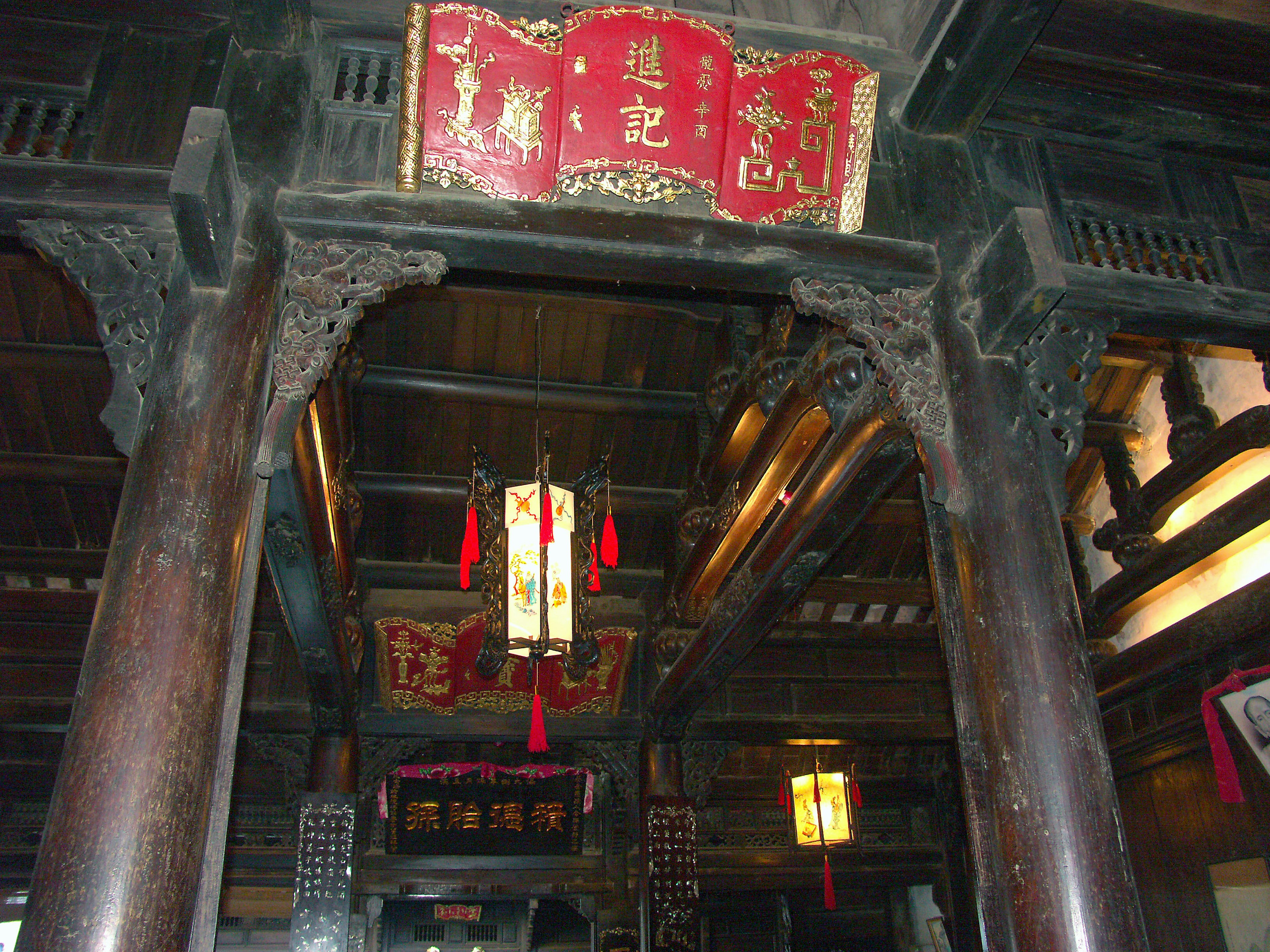 Interno di un edificio antico con colonne in legno e insegne rosse decorative