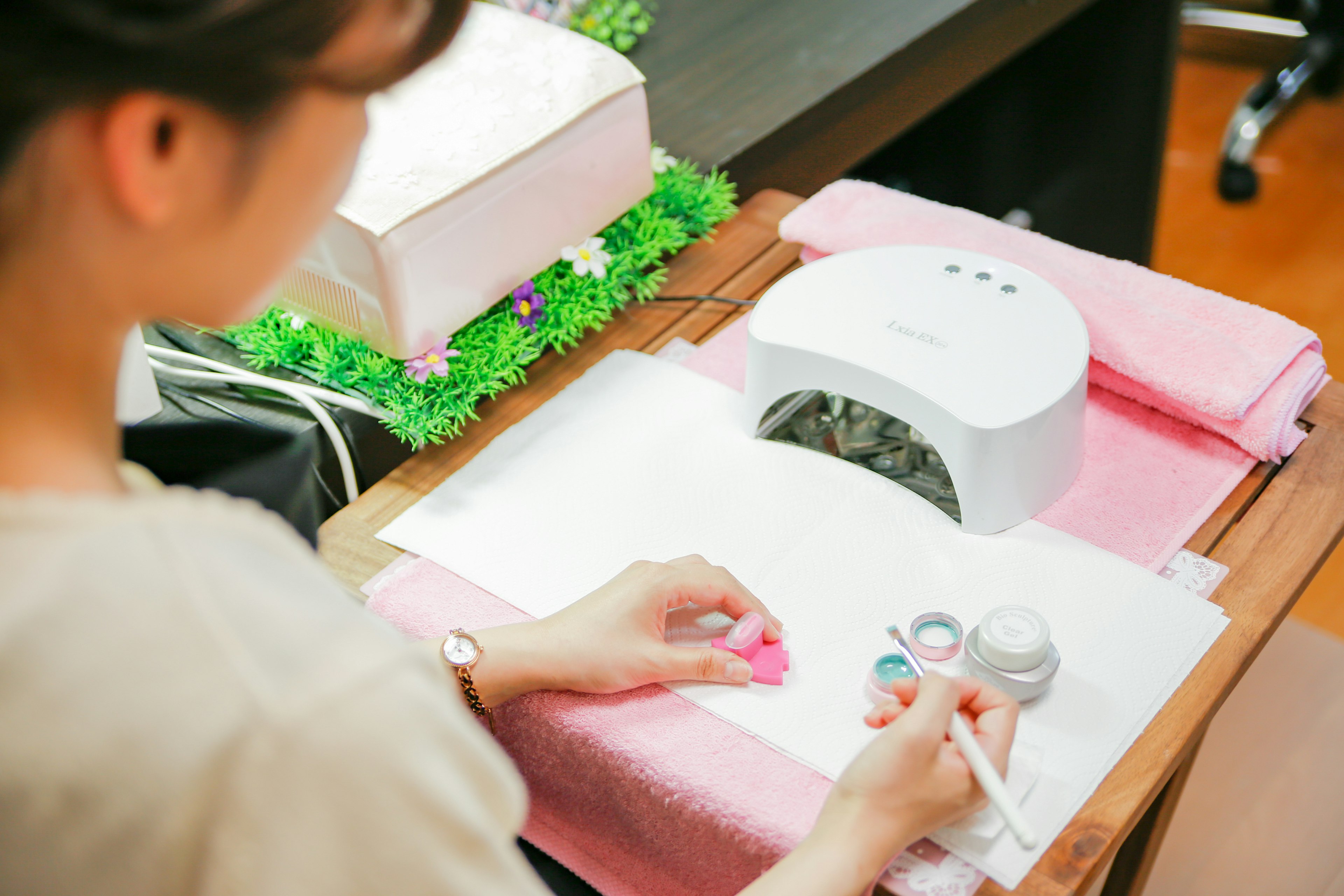 Primo piano di una donna che fa nail art con una lampada per unghie su un tavolo