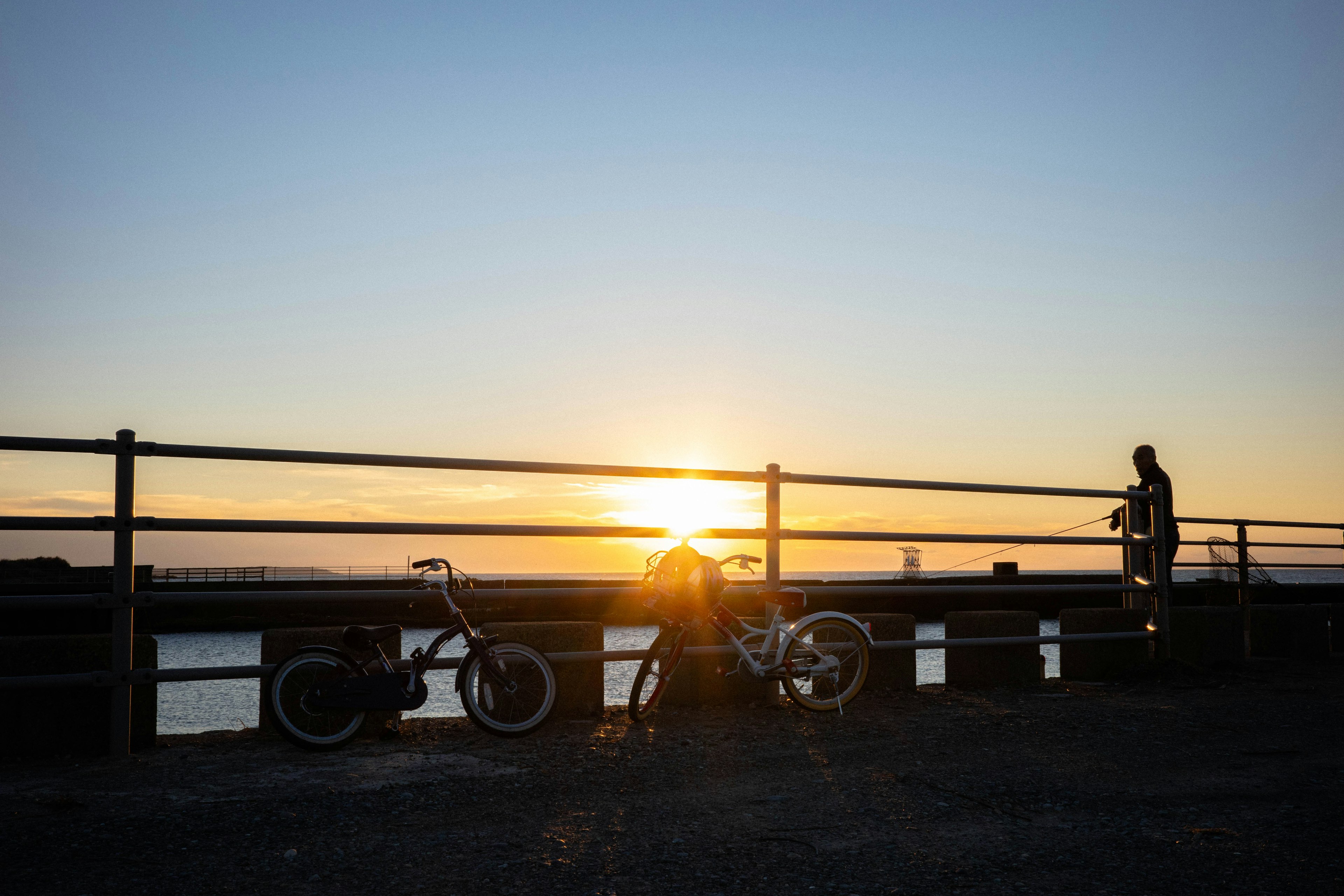 夕日を背景にした自転車と人物のシルエット