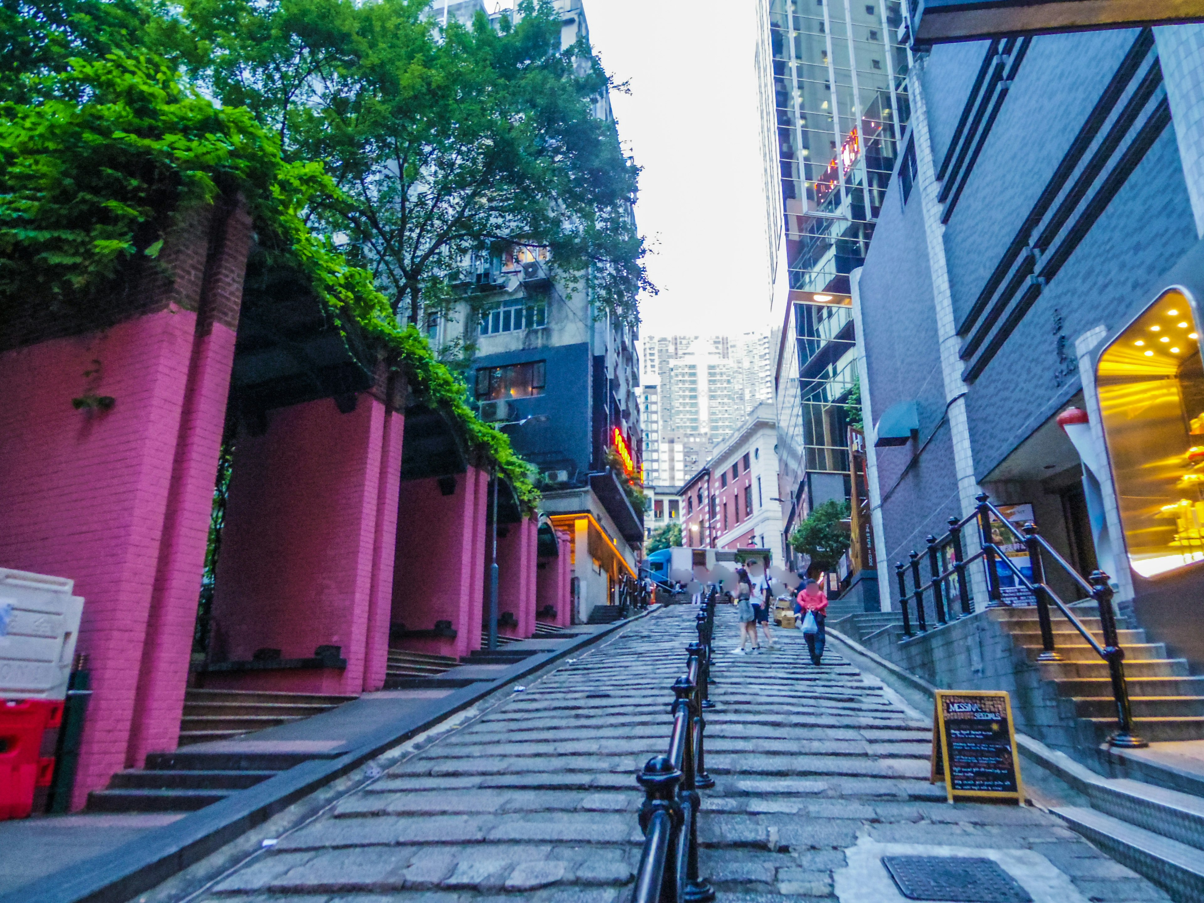 Steep street lined with vibrant buildings and greenery in an urban setting