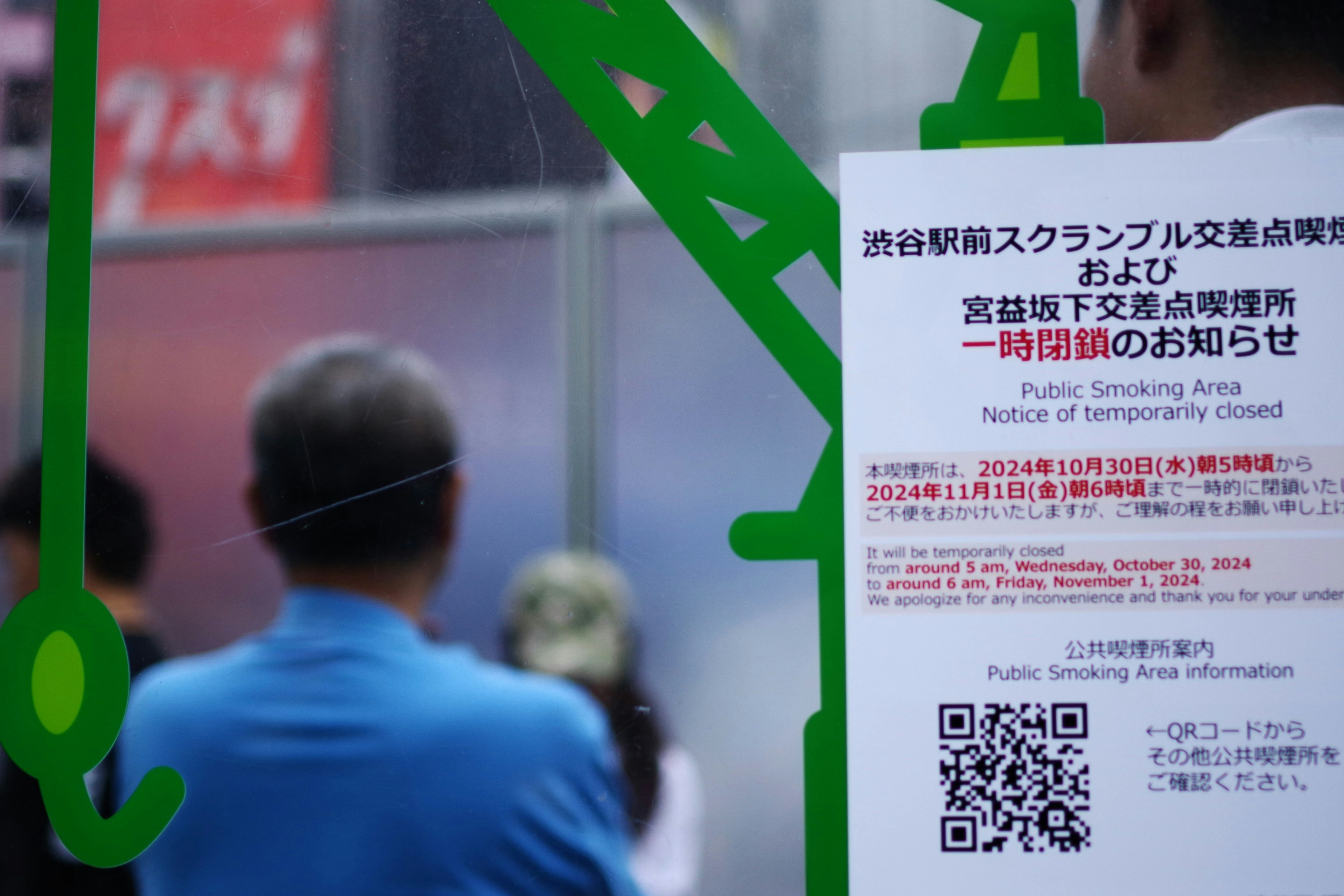 Des personnes regardent un avis avec un code QR et du texte en japonais