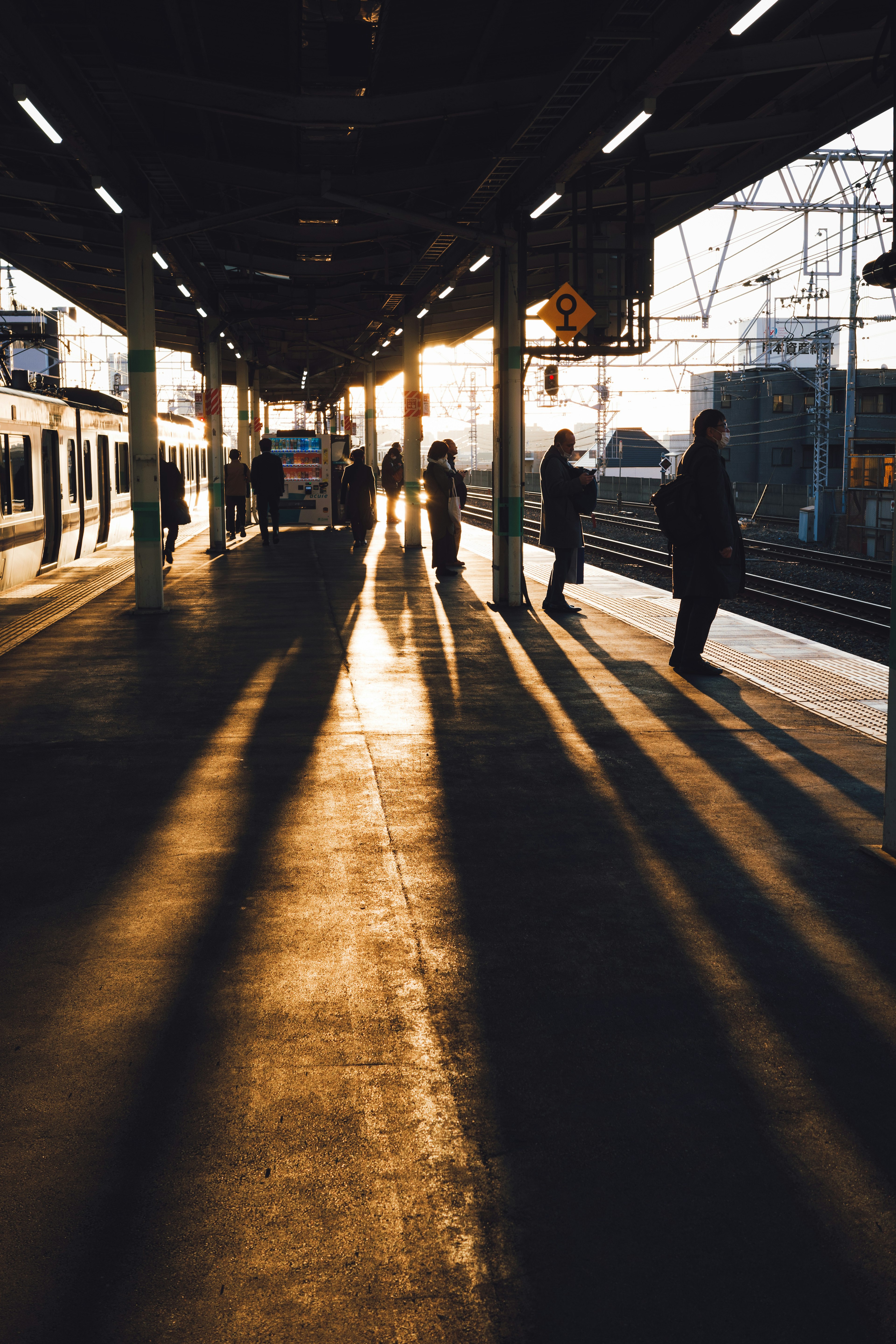 Platform saat matahari terbenam dengan bayangan panjang dari penumpang