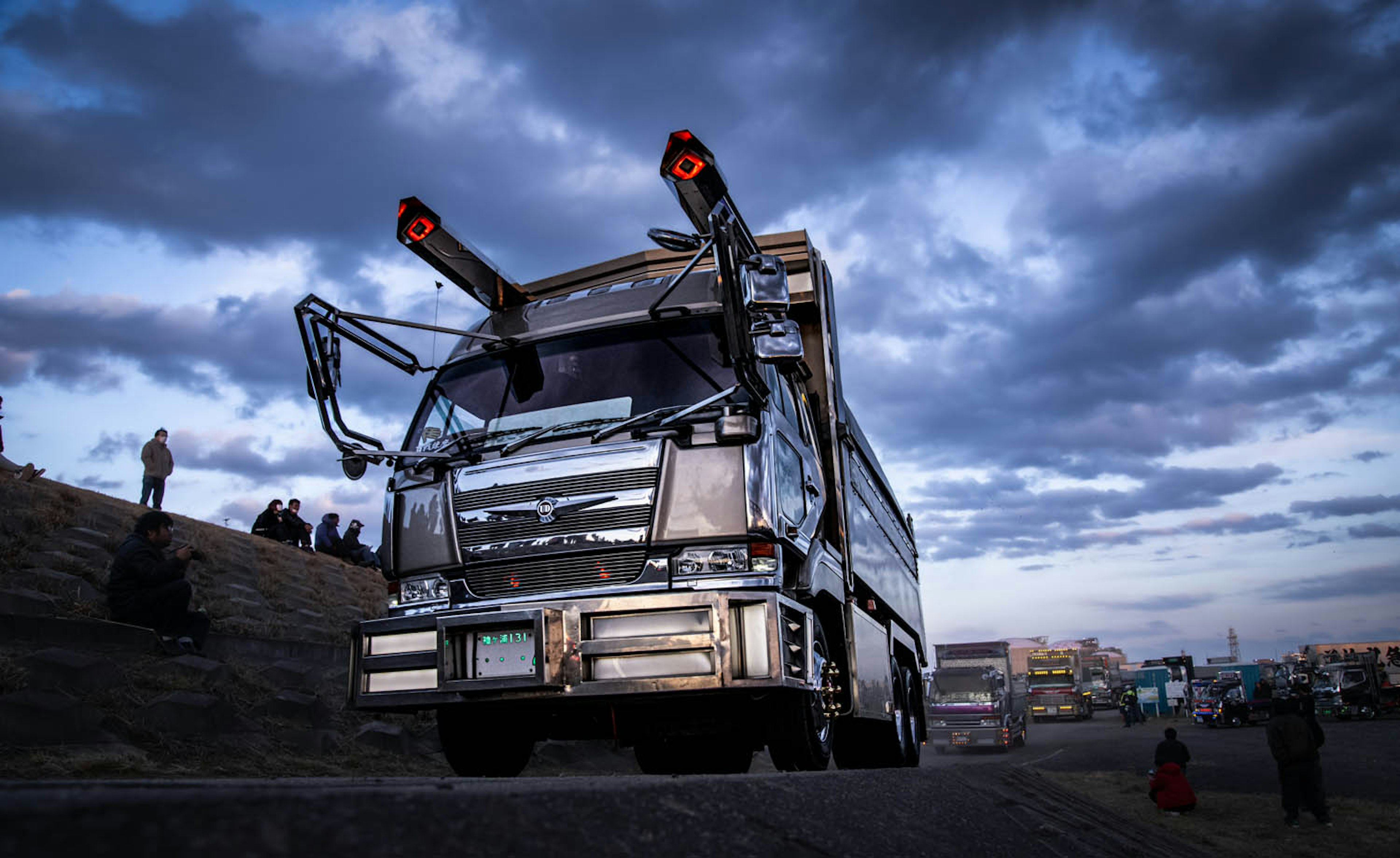 A large metallic truck with unique features against a dramatic sky