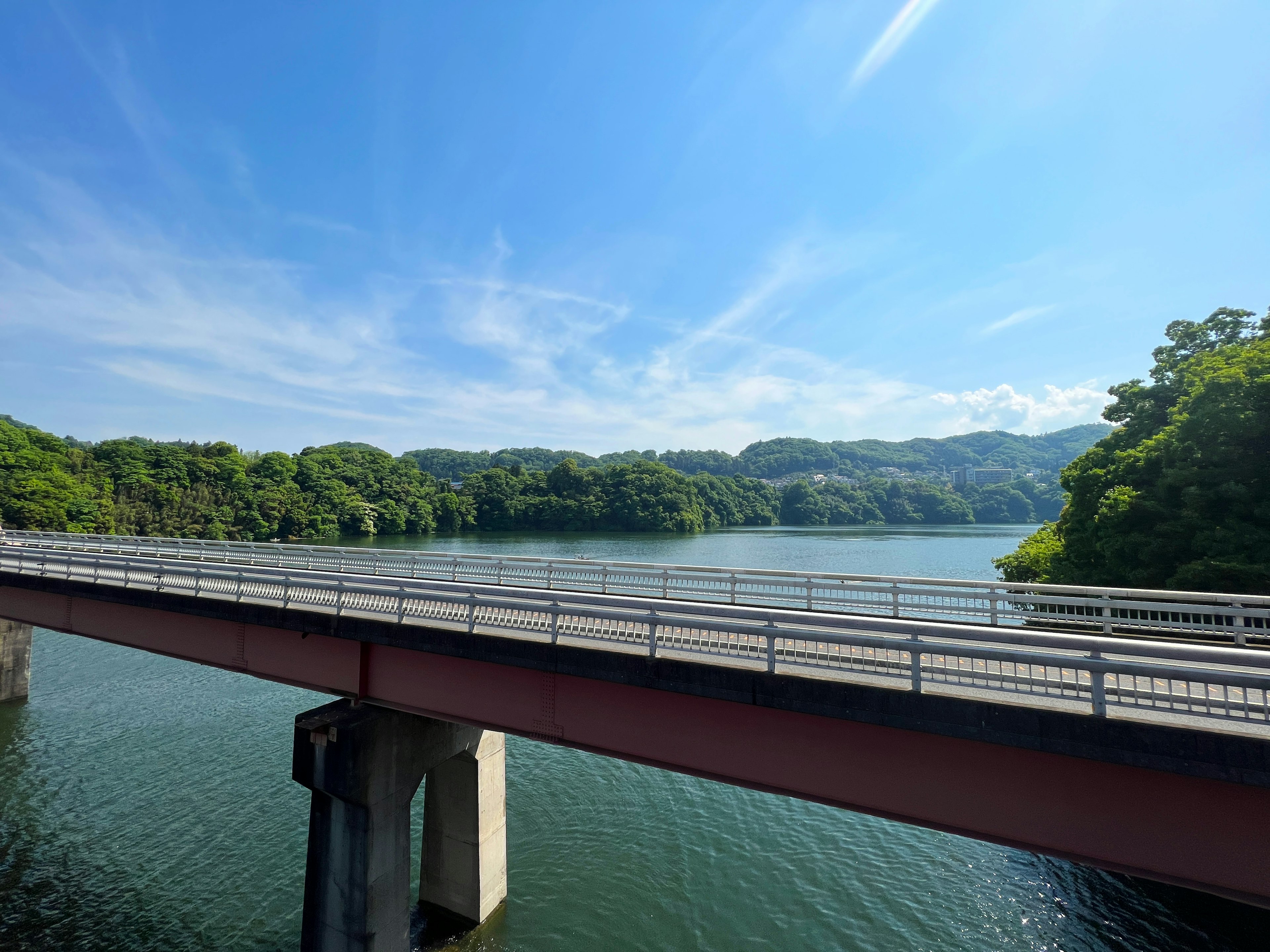 Vista panoramica di un ponte su un lago circondato da alberi verdi e cielo blu