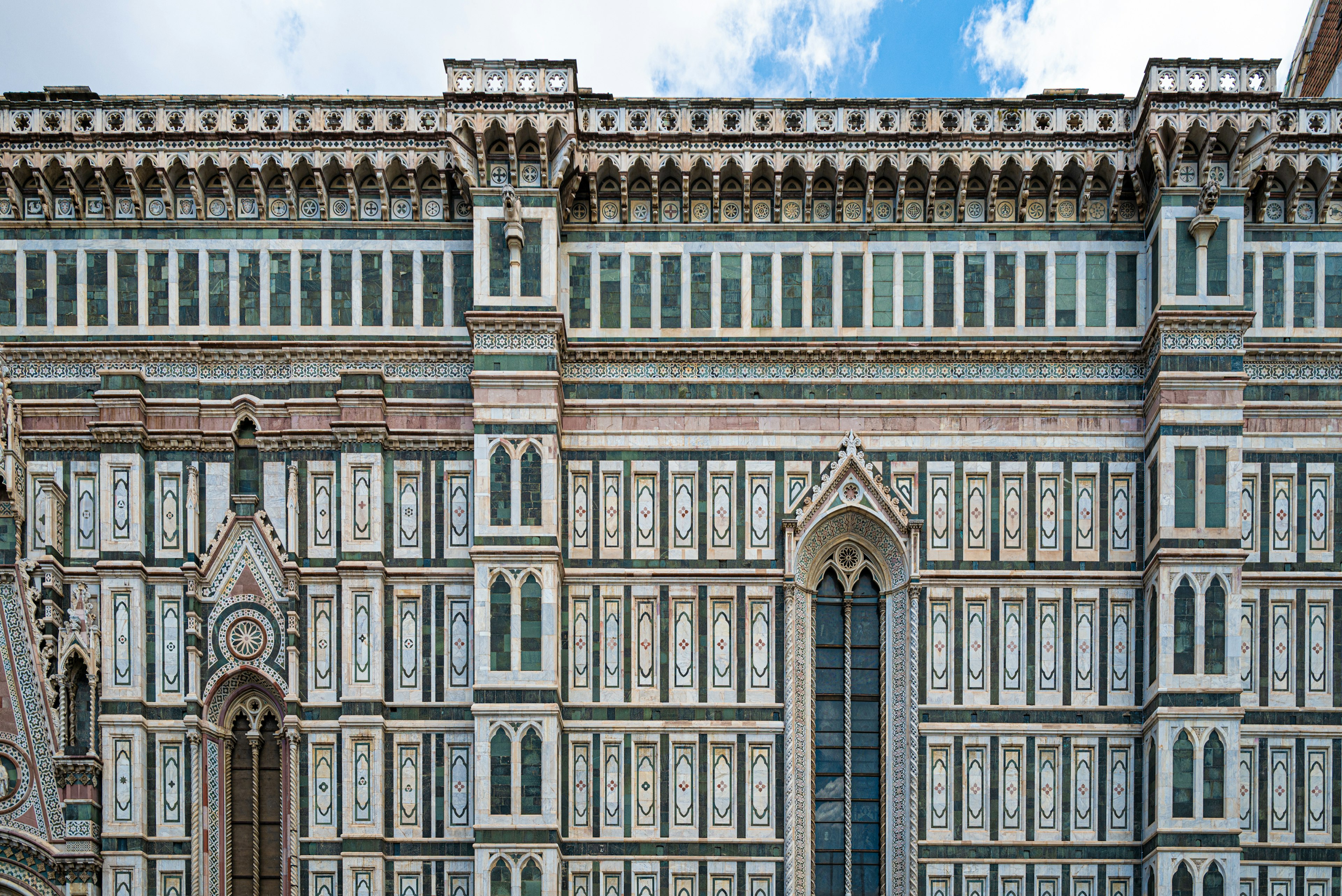 Fachada decorativa de la catedral de Florencia con ventanas intrincadas y detalles arquitectónicos