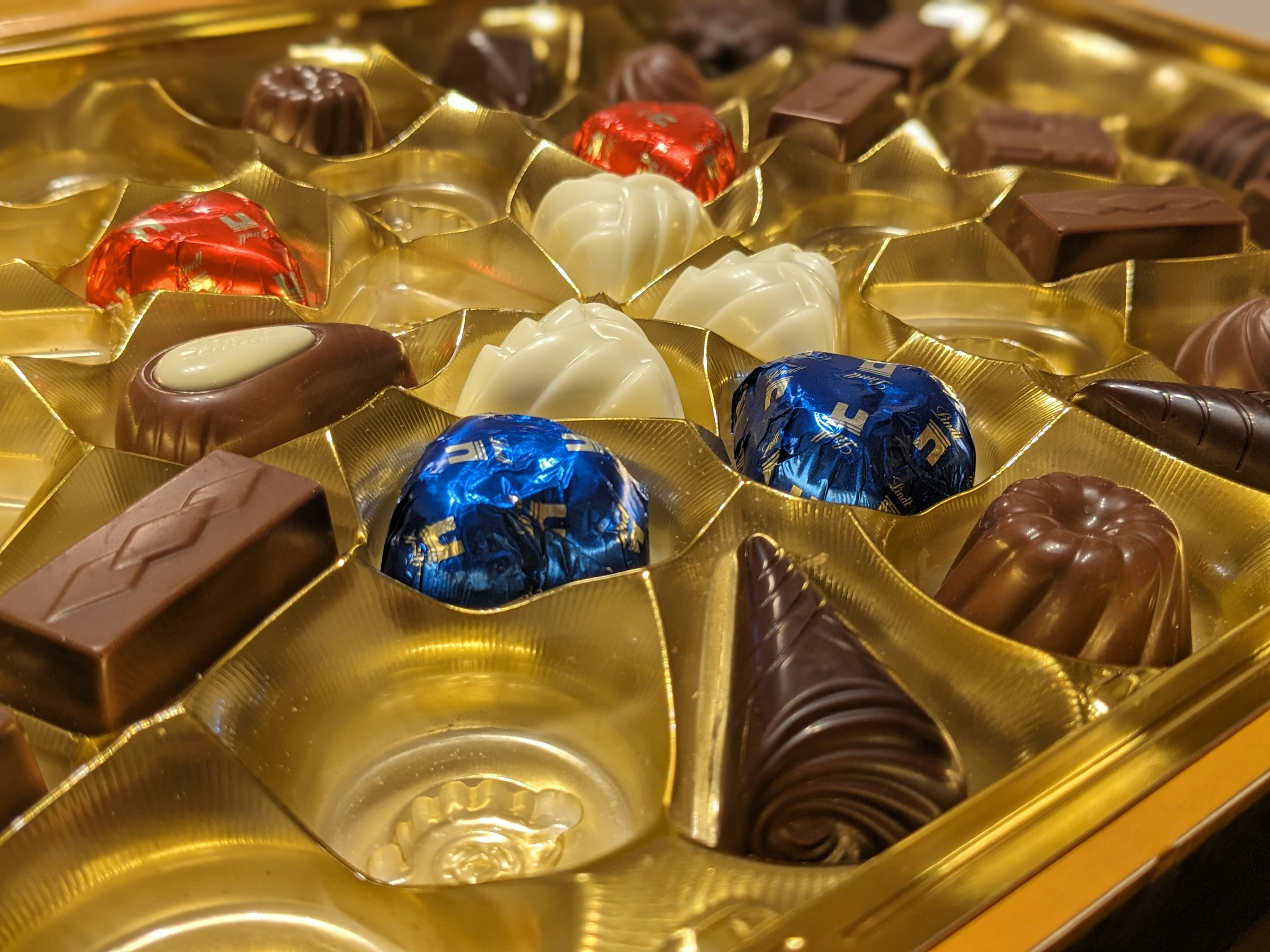 Un assortiment de chocolats colorés disposés dans un plateau doré