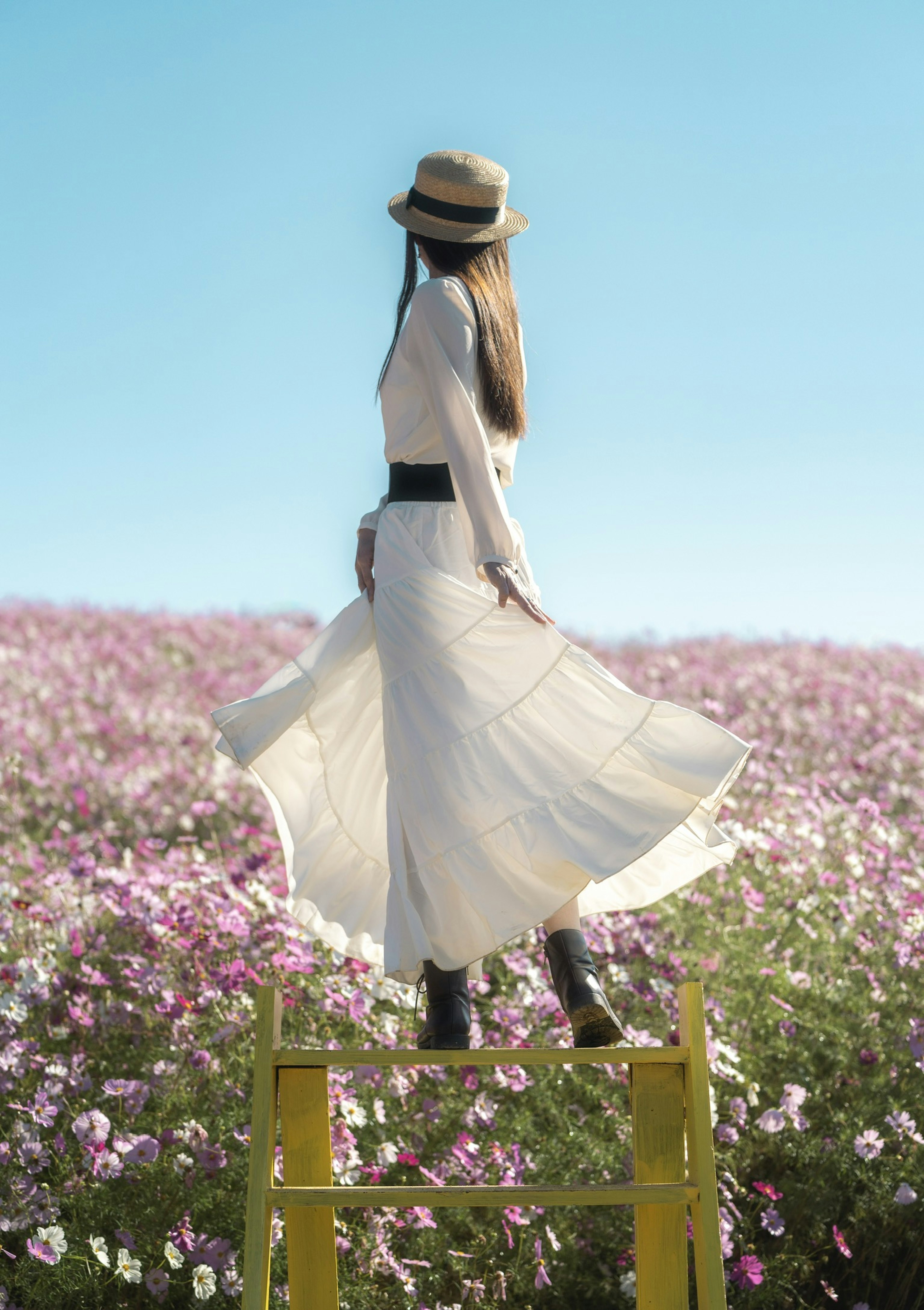 Une femme en robe blanche se tenant dans un champ de fleurs