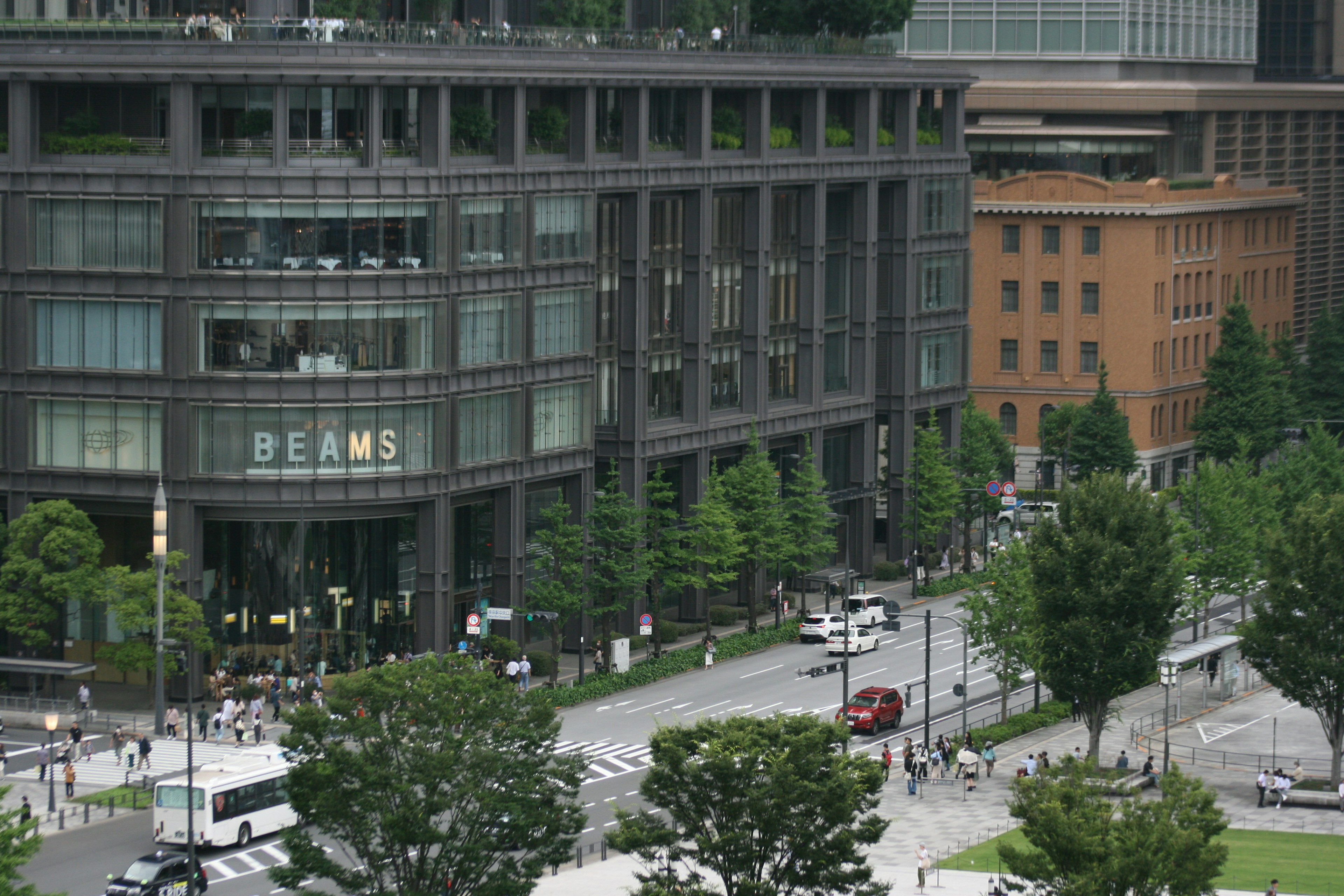 現代的なビルと緑豊かな街路の風景 BEAMS の看板が目立つ