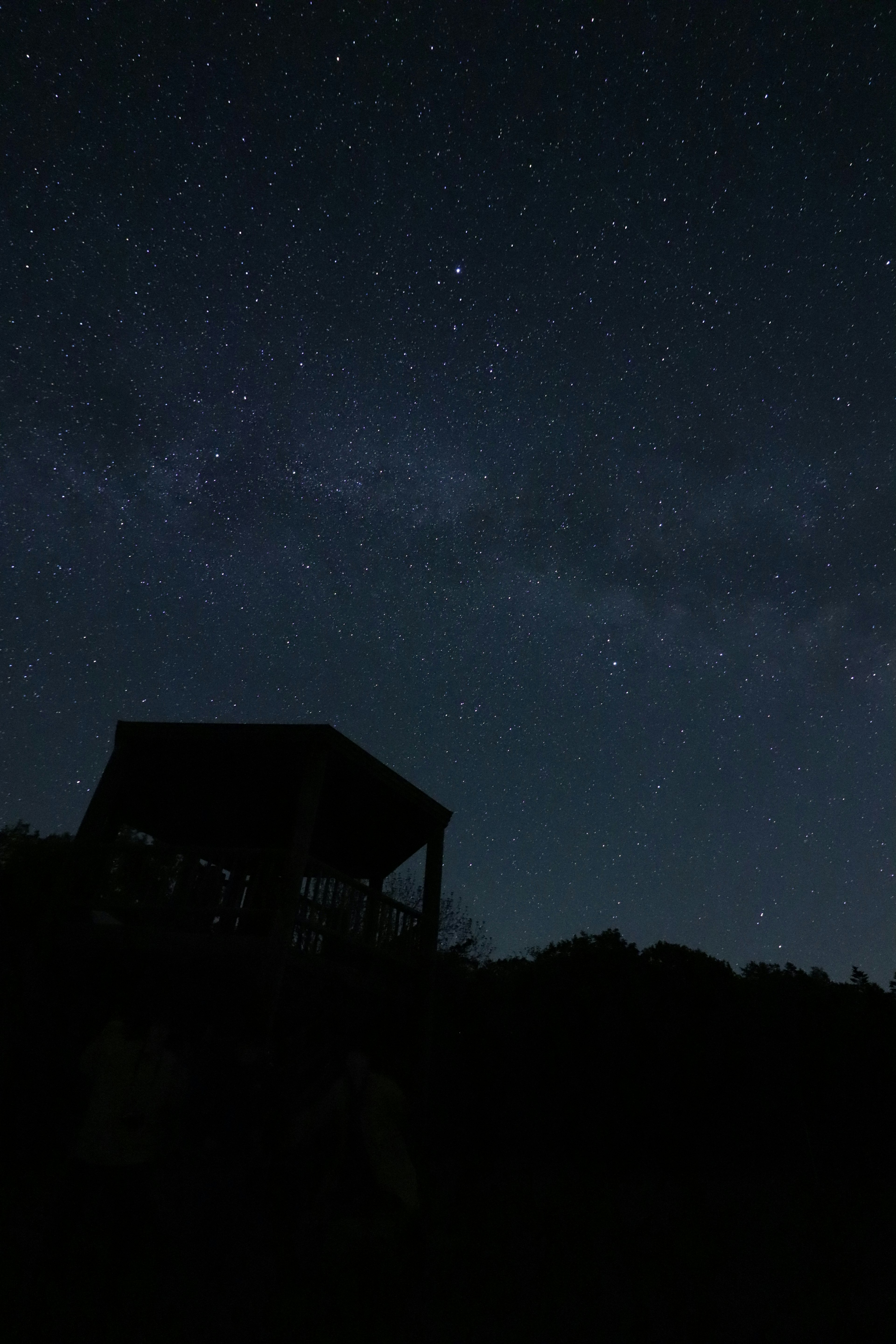 星空とシルエットの小屋が映る夜の風景